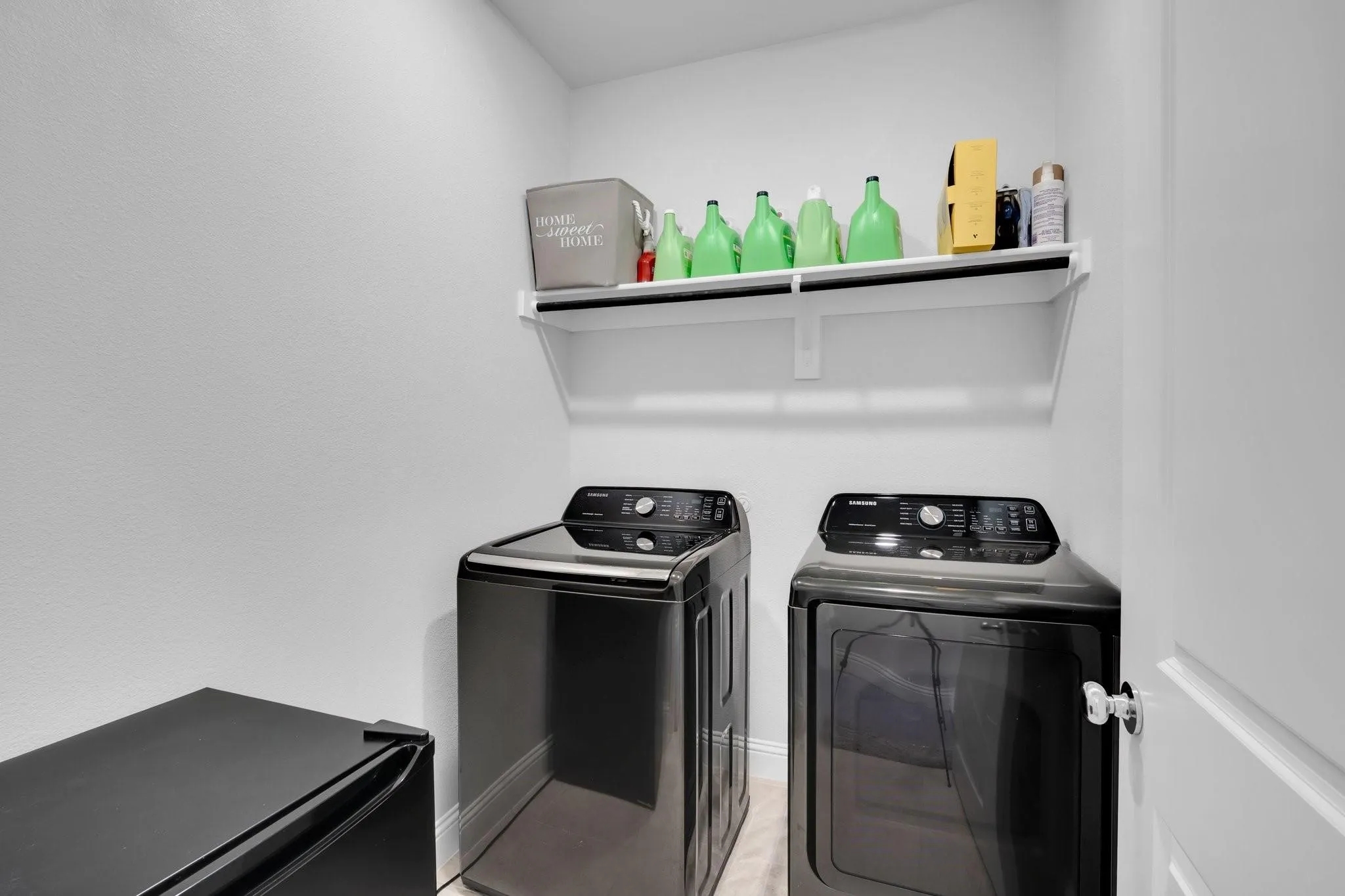 Dedicated laundry area featuring a white wall shelf, textured white walls, and bright white trim