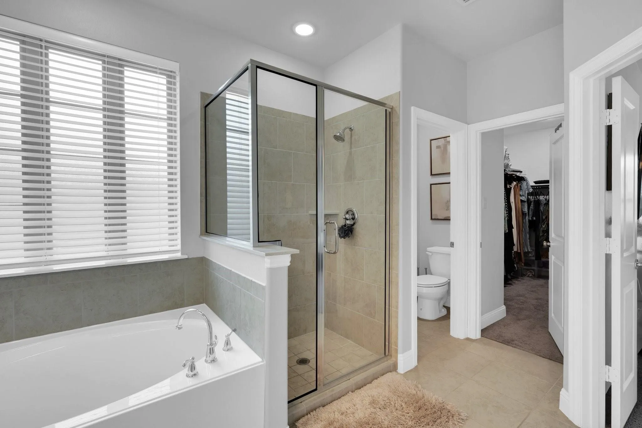 Contemporary bathroom featuring a built-in soaking tub, a glass-enclosed shower with tiled walls, chrome fixtures, and a window with horizontal blinds
