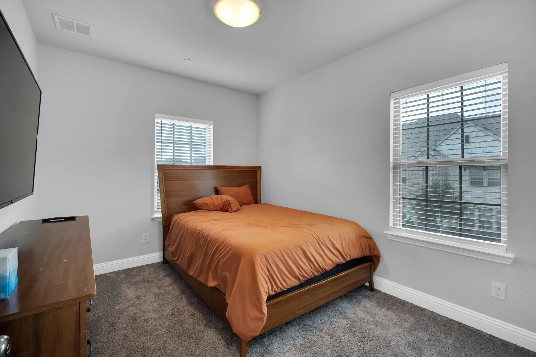Carpeted room featuring two windows with horizontal blinds, light gray walls, and a flush mount ceiling light