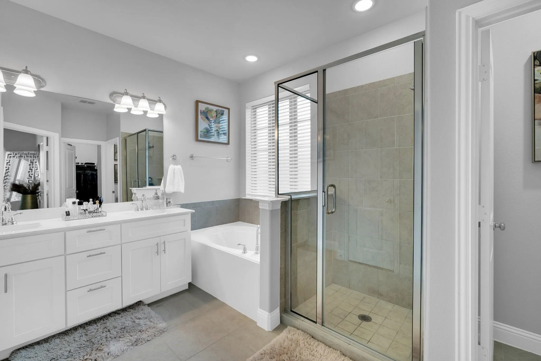 Glass-enclosed shower with tiled walls and floor, accompanied by a separate soaking tub