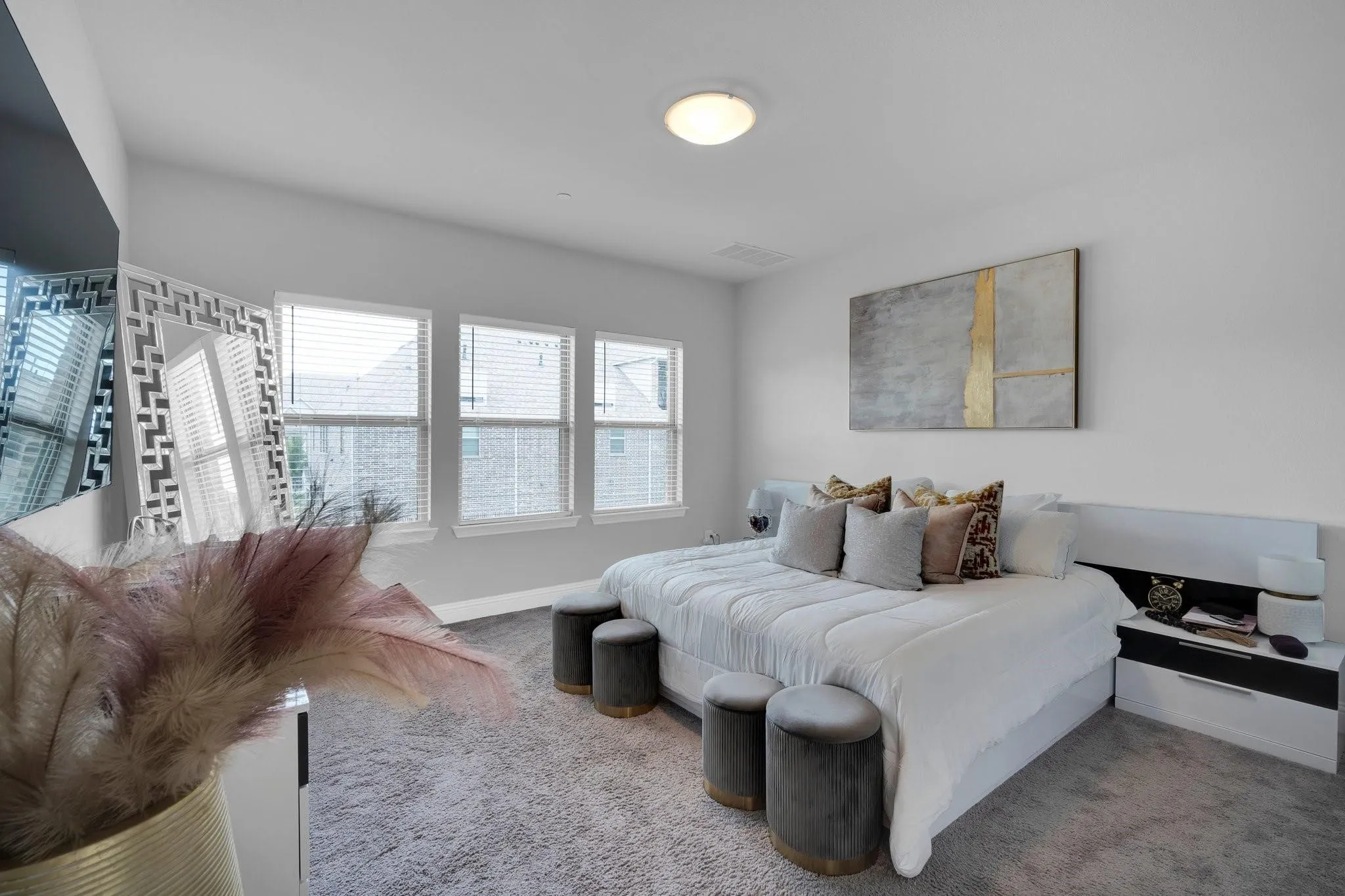 Carpeted room featuring three windows with blinds, a built-in headboard with integrated lighting, and white walls