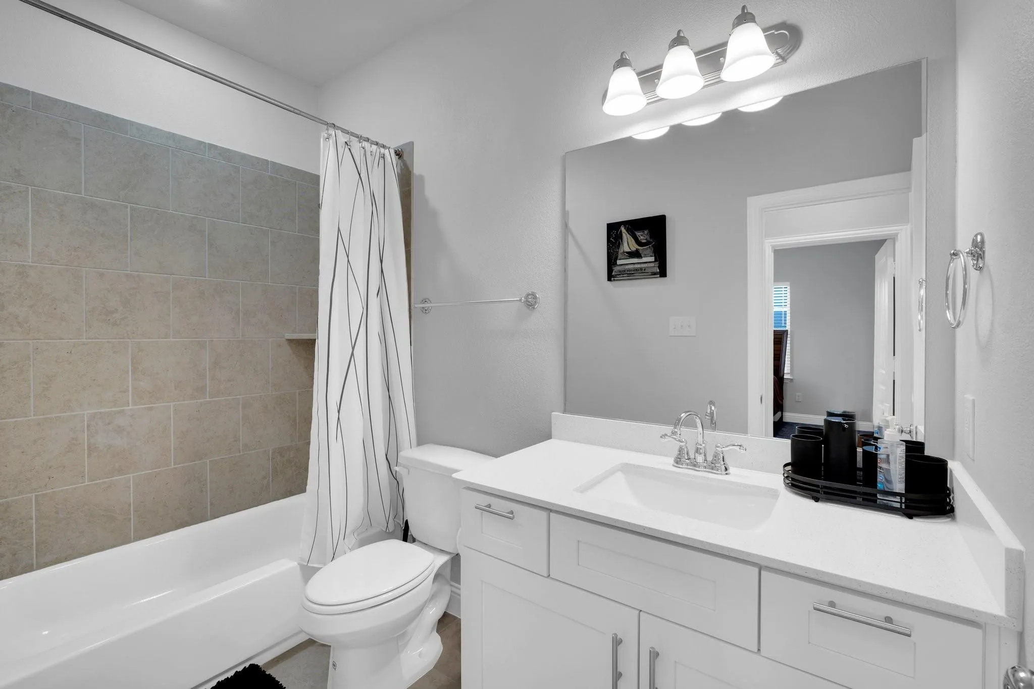 Full bathroom featuring a white vanity with integrated sink, a large mirror, and a three-light fixture