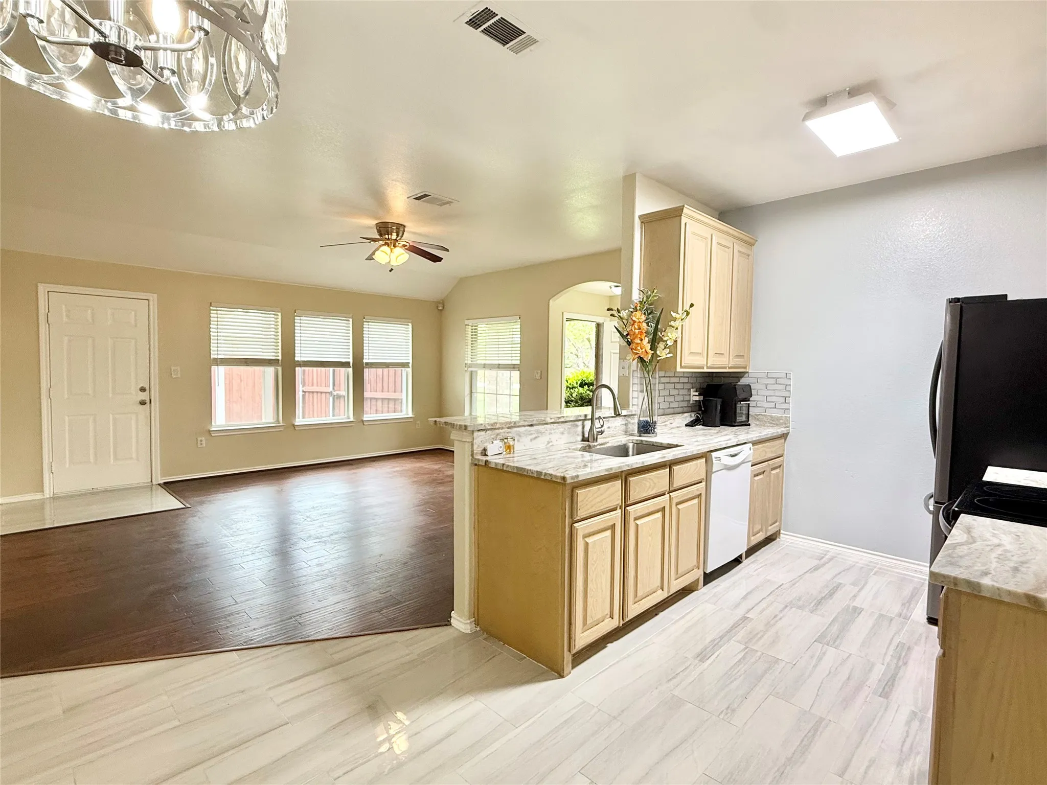 Kitchen featuring light-toned cabinetry, granite countertops, a white subway tile backsplash, and stainless steel appliances