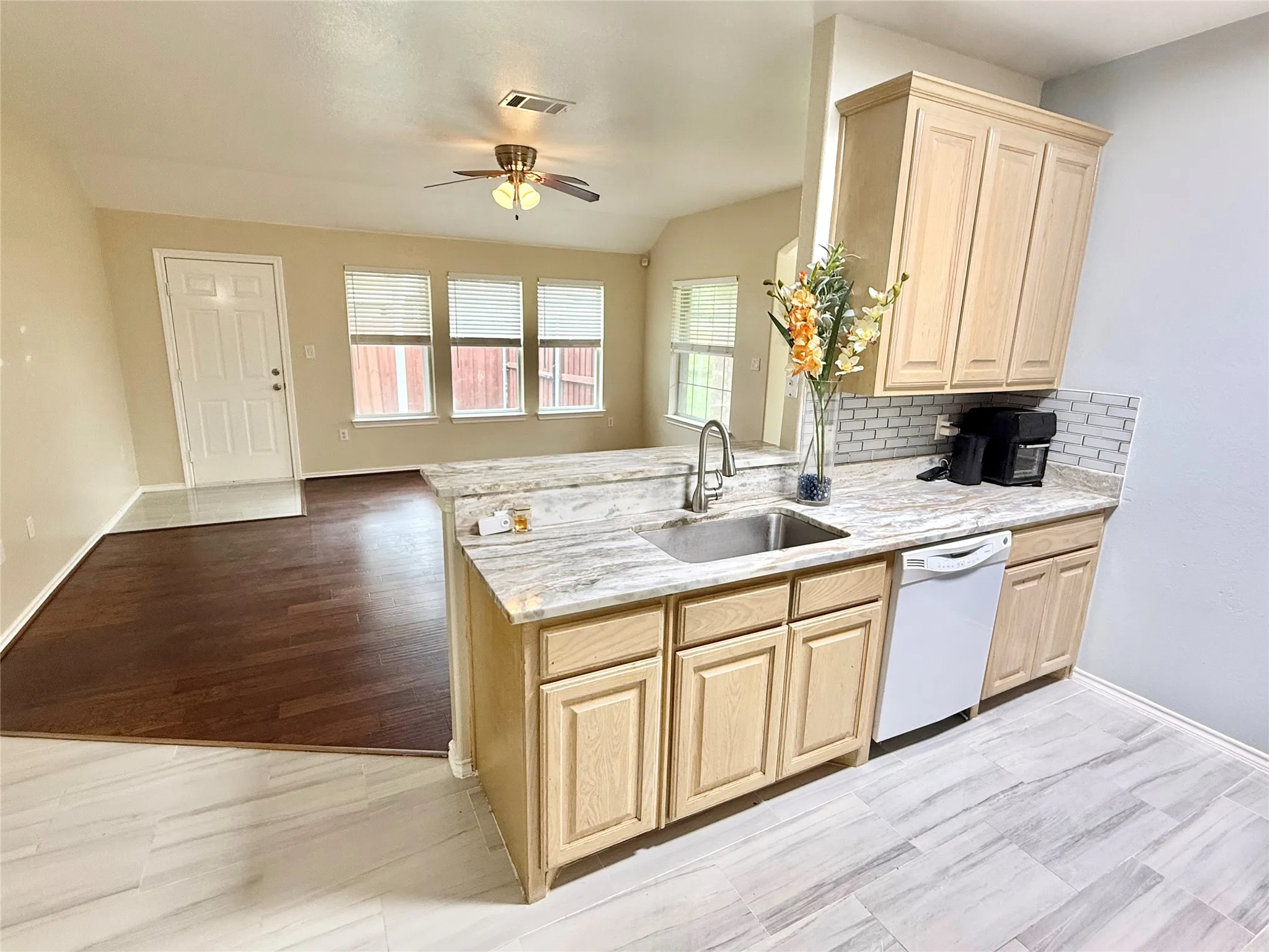 Kitchen featuring light wood cabinetry, a stainless steel sink, and a white dishwasher
