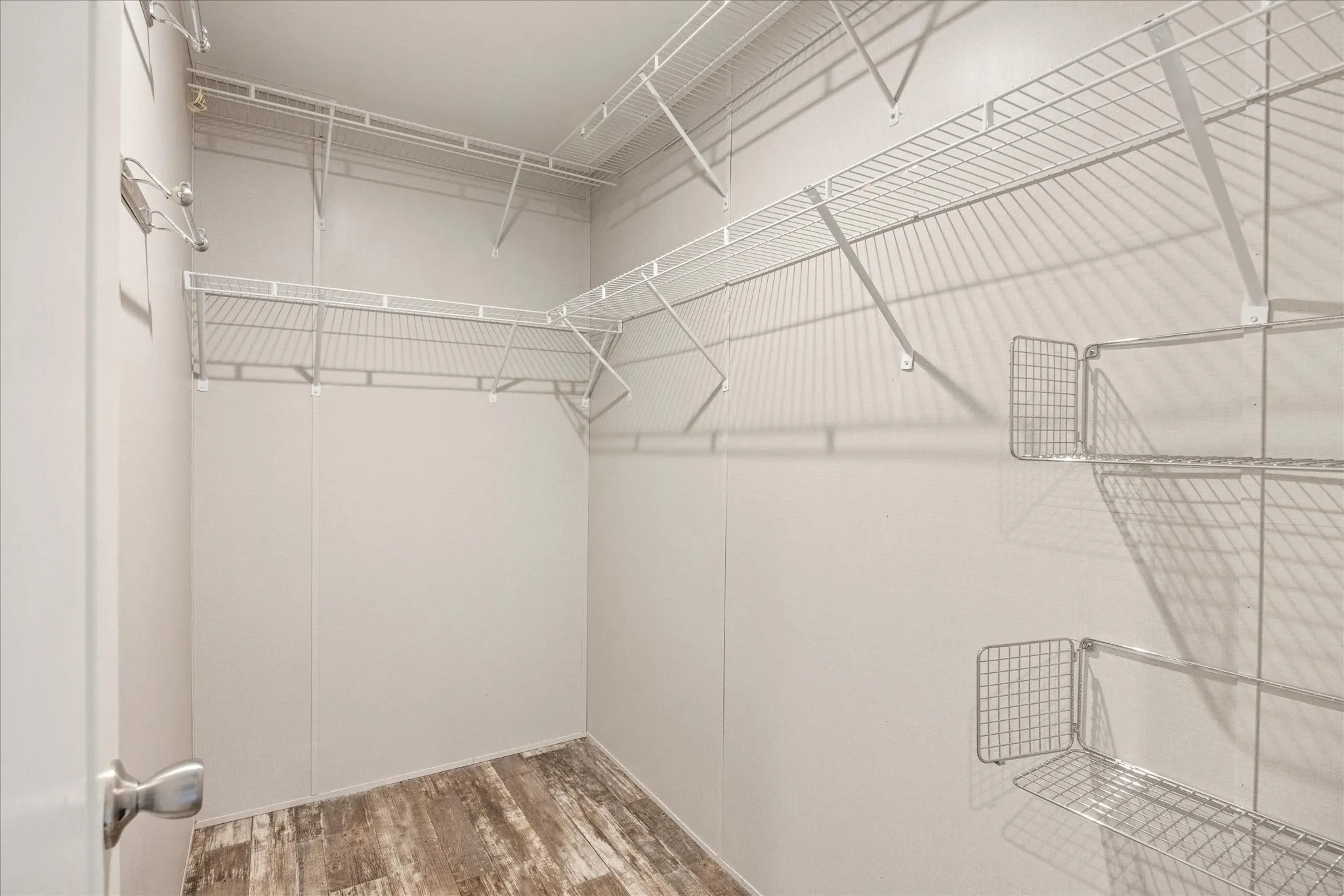 Spacious walk-in closet featuring wire shelving, hanging rods, and wood-finish flooring