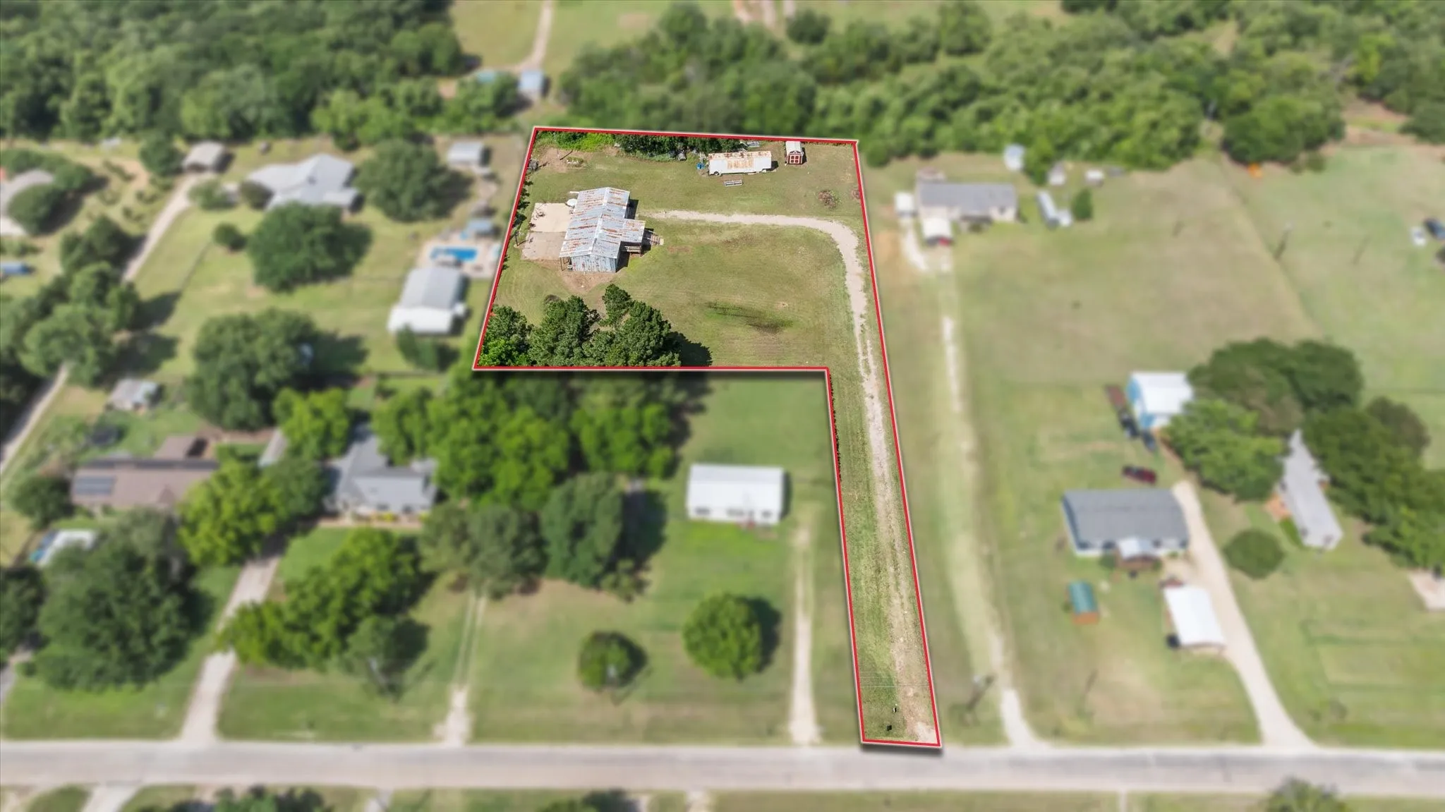 Estimated lot lines for photos only Expansive lot featuring a single-story residence with a light-colored roof, multiple outbuildings, mature trees, and a long driveway extending to the road