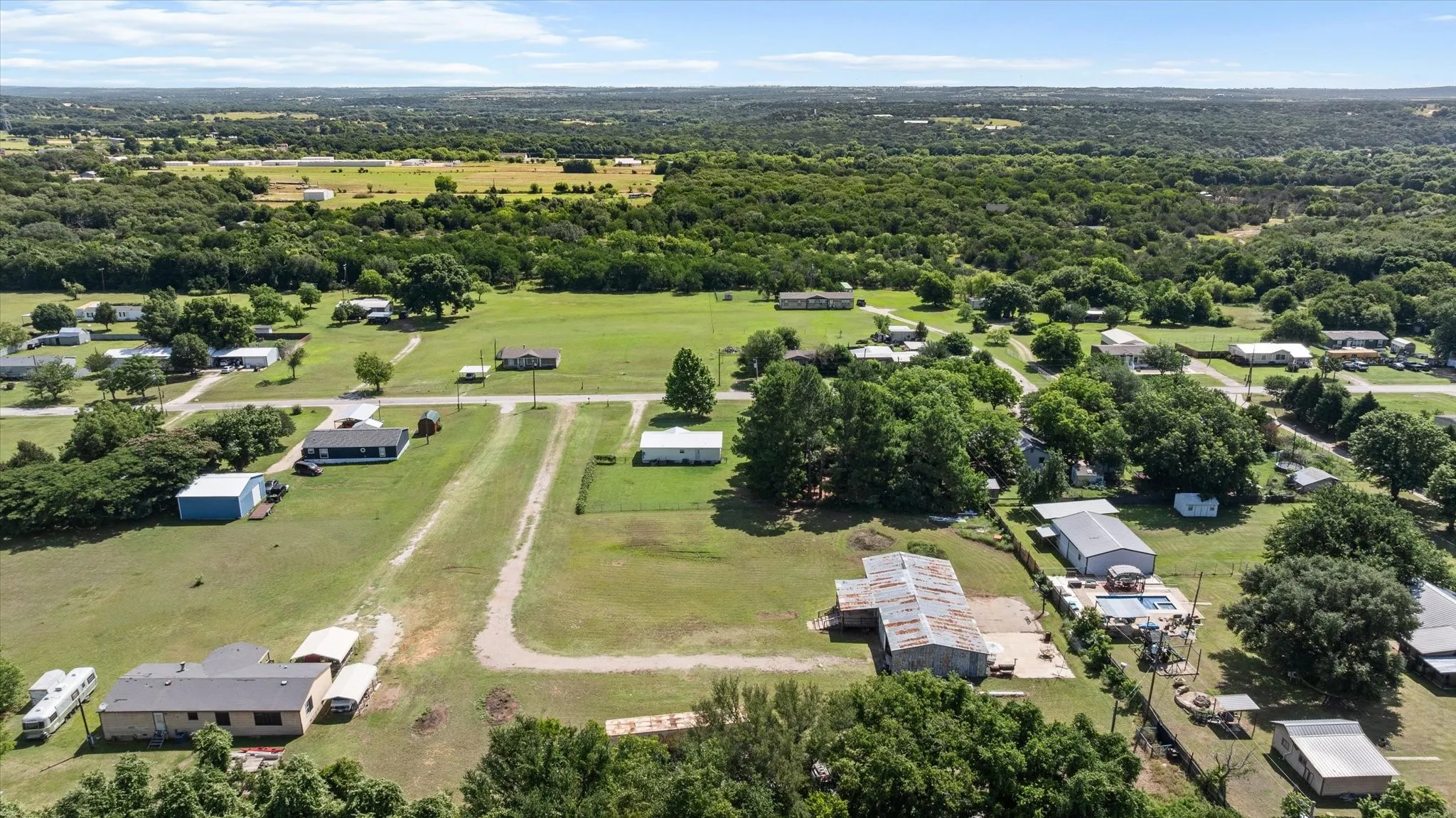 Expansive rural landscape featuring scattered residences, abundant mature trees, and open green spaces