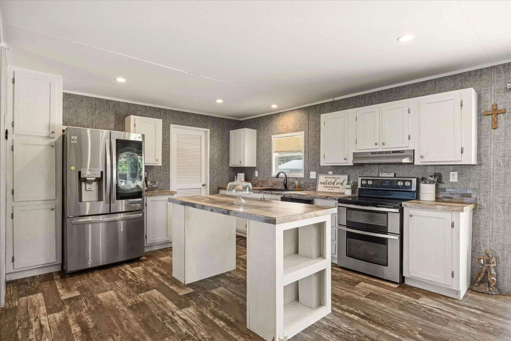 Kitchen featuring wood-finish flooring, white cabinetry, a central island with countertop seating, and stainless steel appliances including a double oven range and a French door refrigerator