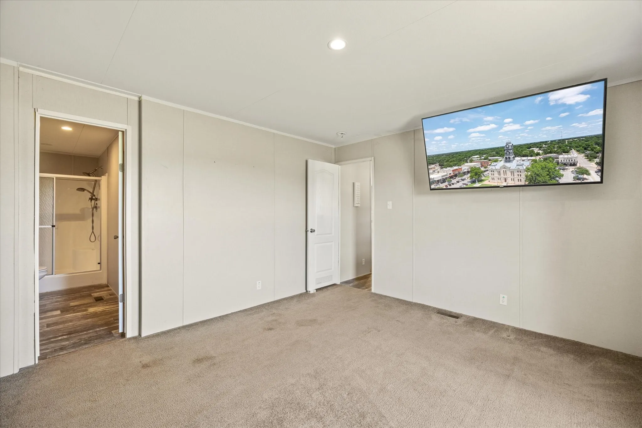 Spacious room featuring neutral carpet flooring and light-toned wall paneling