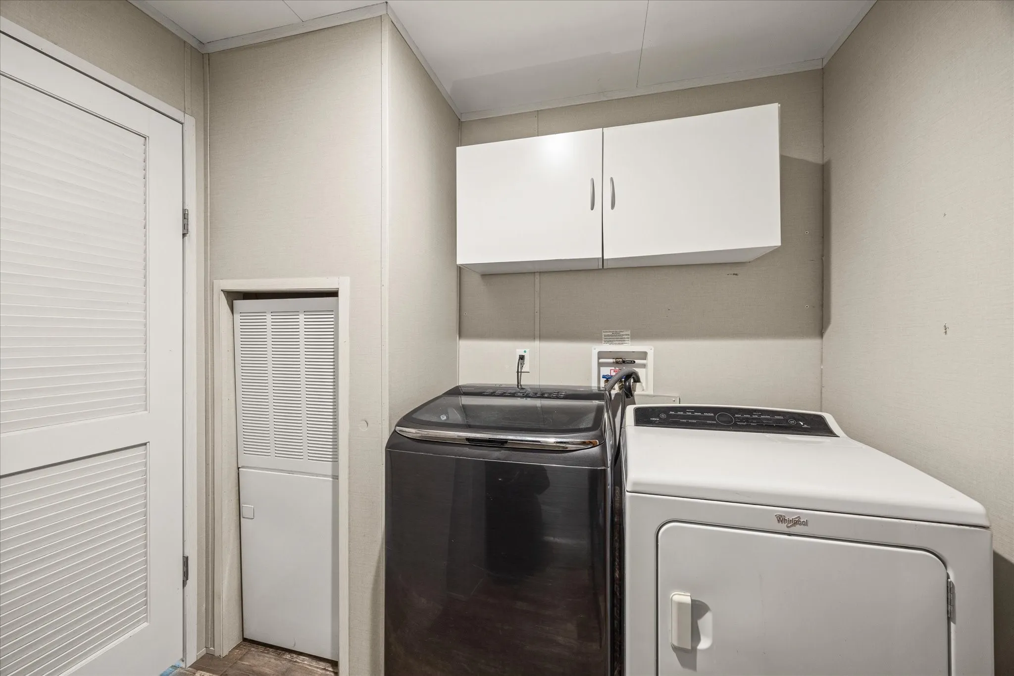 Dedicated laundry area featuring wall-mounted cabinetry, washer/dryer hookups, and a louvered door