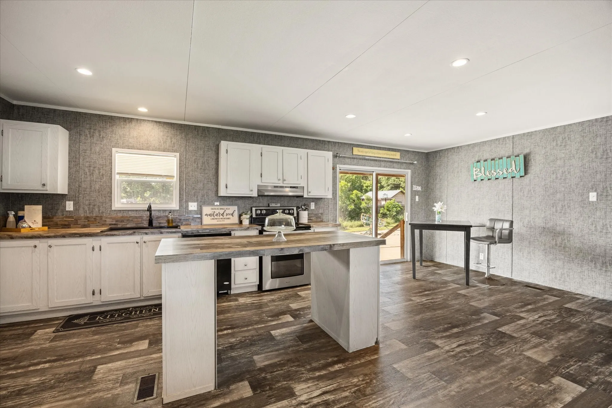 Spacious kitchen featuring white cabinetry, a large center island with countertop, wood-finish flooring, and recessed lighting