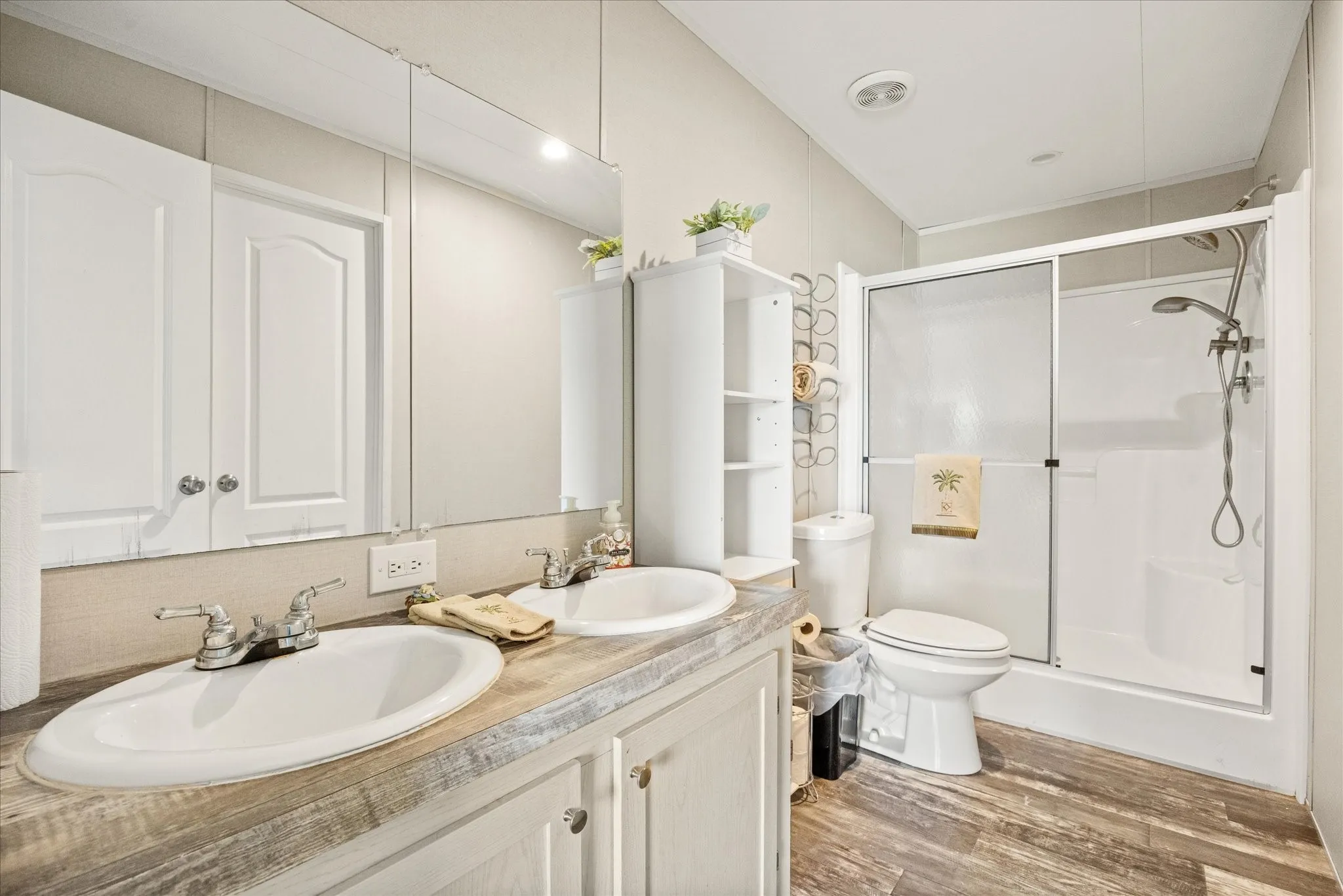 Bathroom featuring a double vanity with wood-finish countertop, dual sinks, and white cabinetry