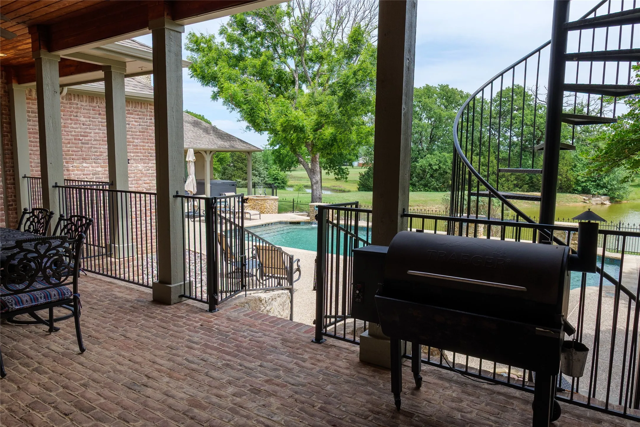 Covered patio area with build-in grill and fenced for privacy over looks and leads to pool area
