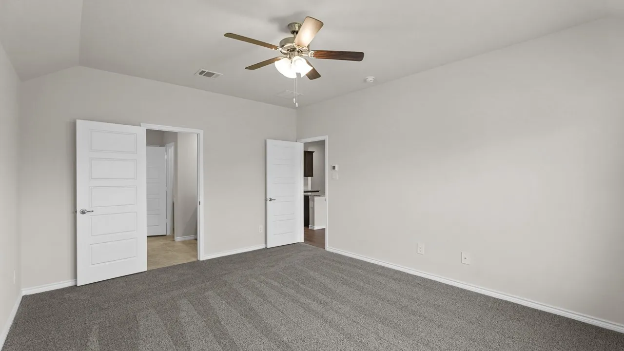 Spacious room featuring vaulted ceilings, light gray wall paint, and gray carpet flooring