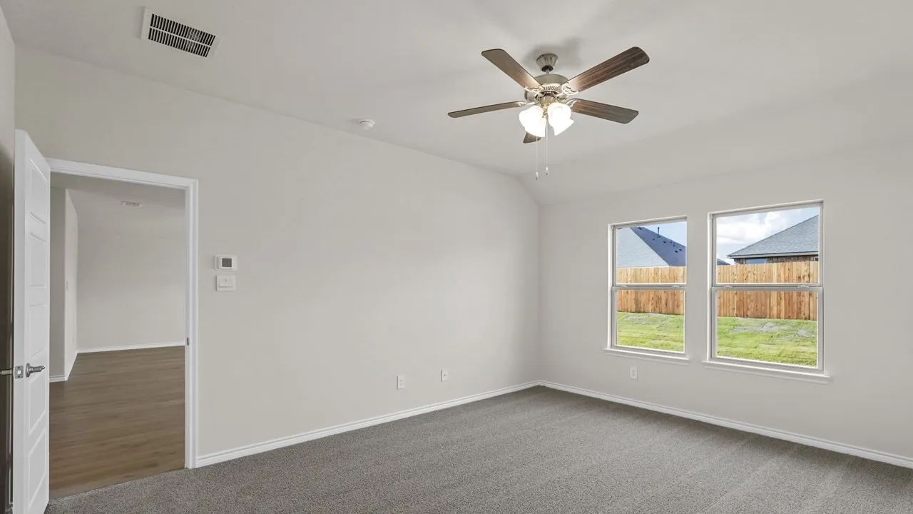 Spacious room featuring carpeting, two windows, a ceiling fan, and a light-colored wall finish