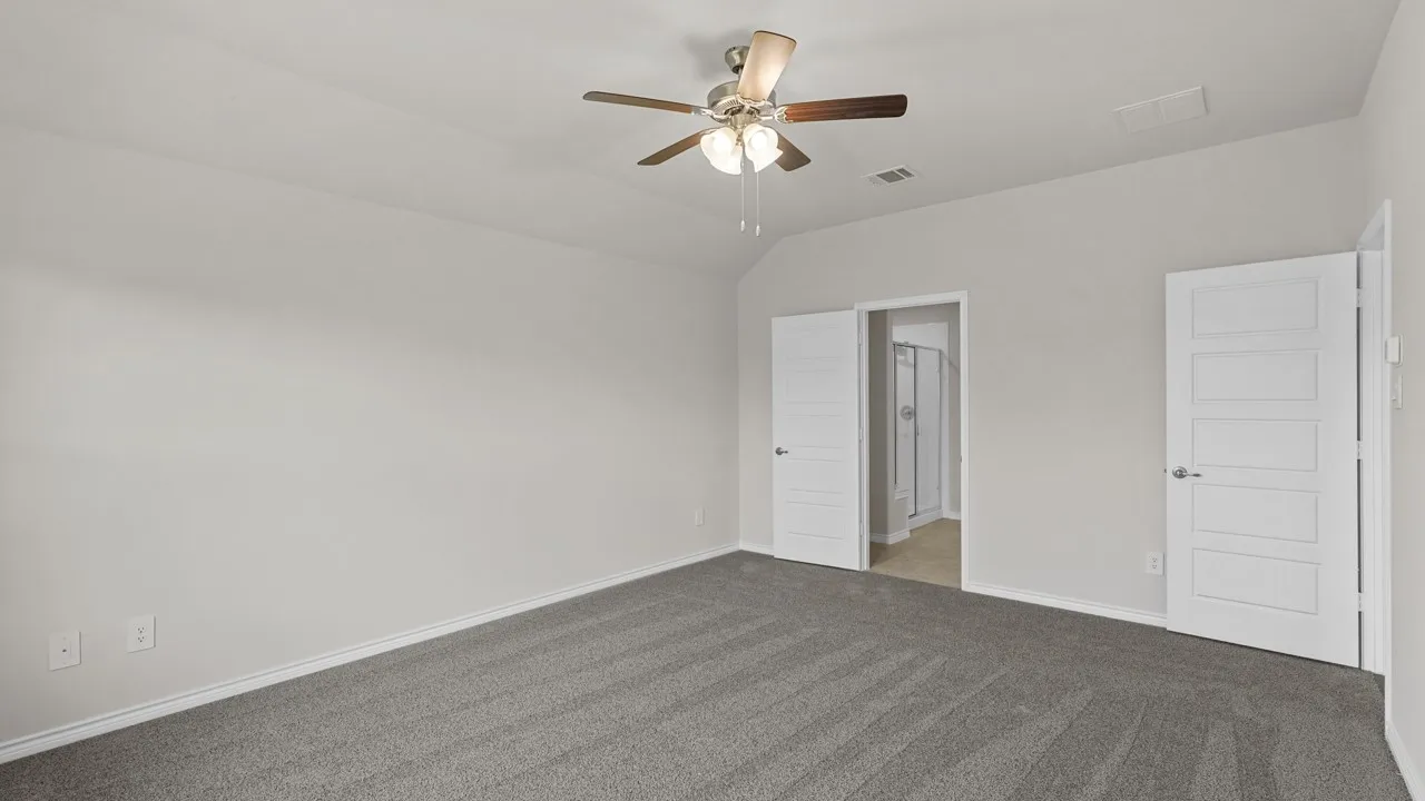 Spacious room featuring vaulted ceilings, a ceiling fan with integrated lighting, and plush grey carpeting