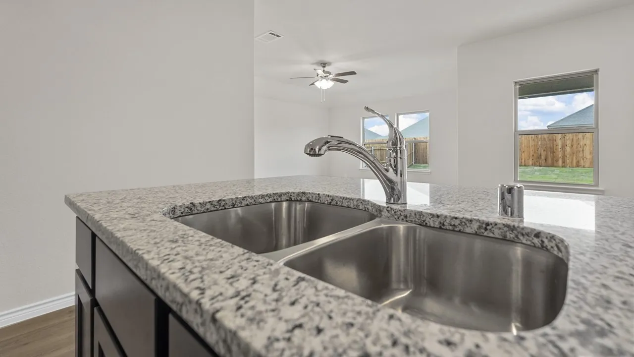 Kitchen island featuring a dual stainless steel sink, granite countertop, and chrome gooseneck faucet