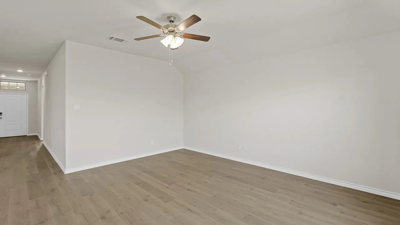 Spacious room with wood-finish flooring, a ceiling fan with integrated lighting, recessed lighting, and a white entry door with an overhead transom window
