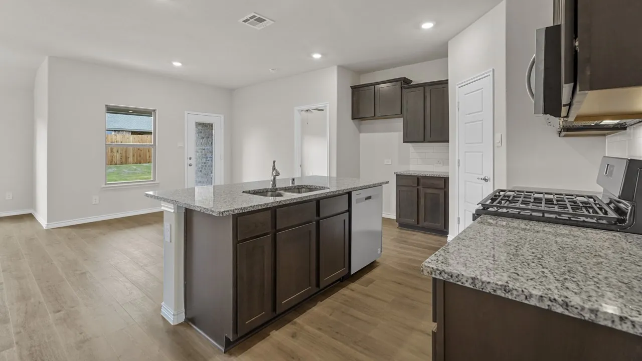 Open-concept kitchen featuring an island with a double basin sink, granite countertops, wood-finish flooring, and recessed lighting