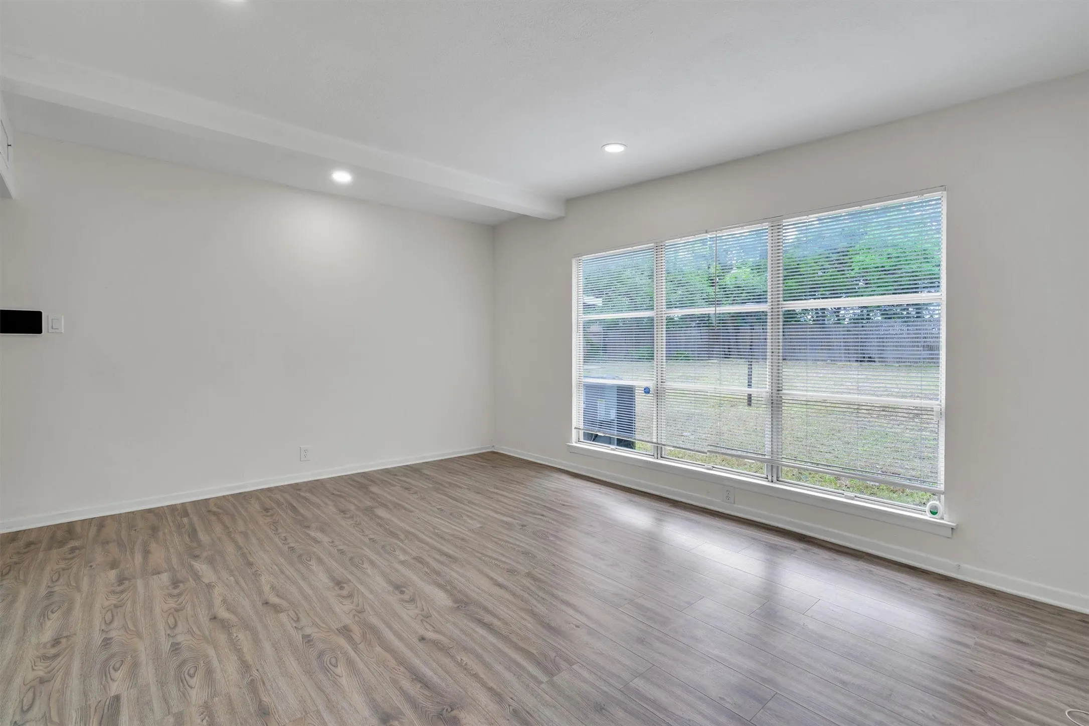 Spacious interior featuring wood-finish flooring, recessed lighting, and white walls