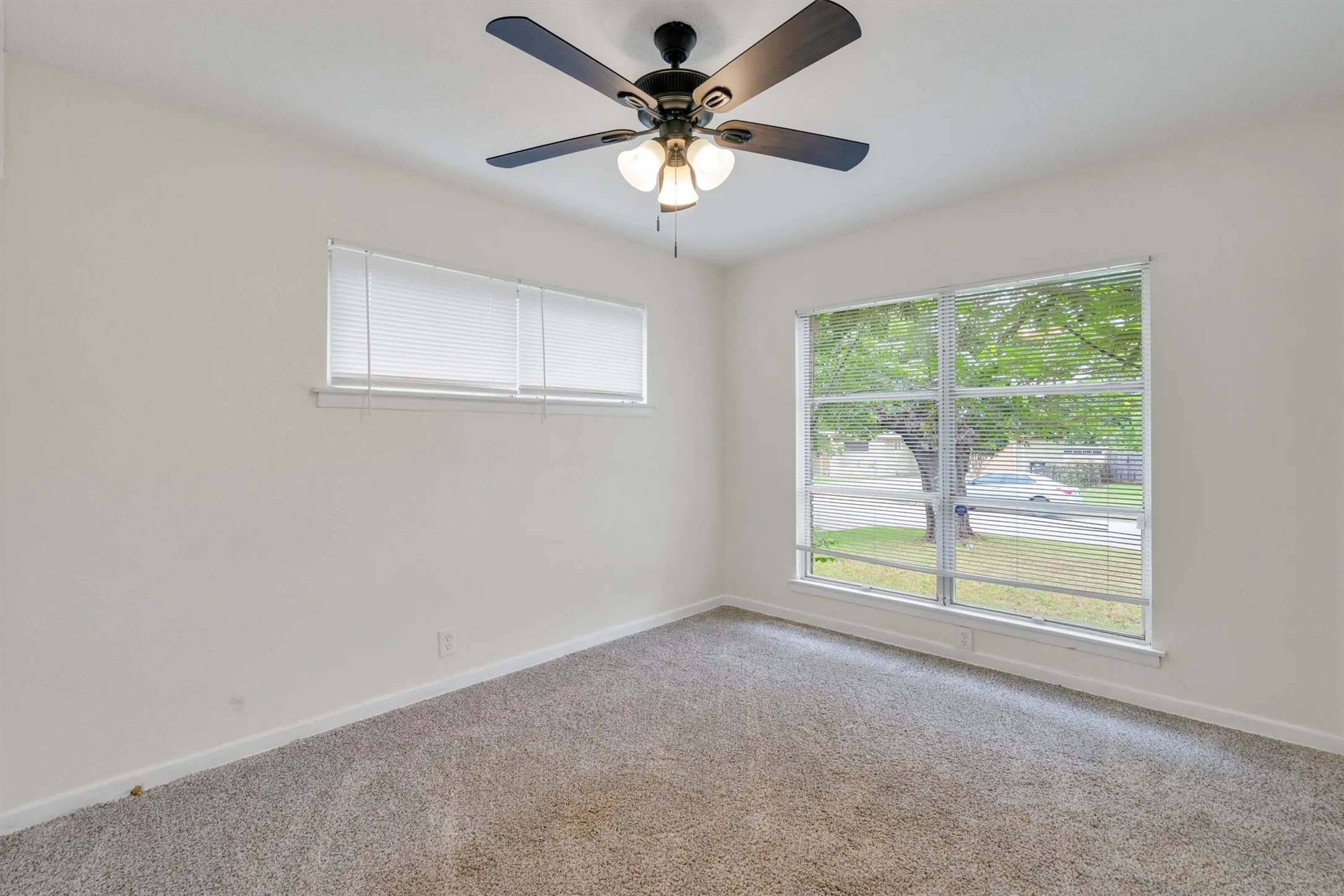 Spacious room featuring neutral carpeting and a ceiling fan with integrated lighting