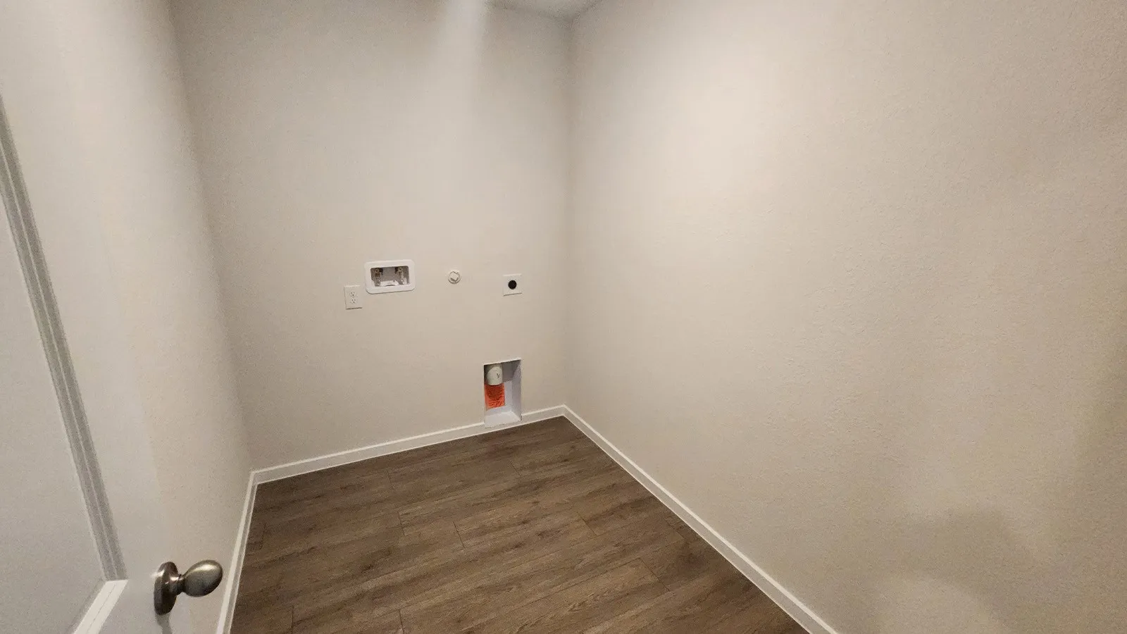 Laundry space featuring light-toned walls, wood-finish flooring, and white baseboards