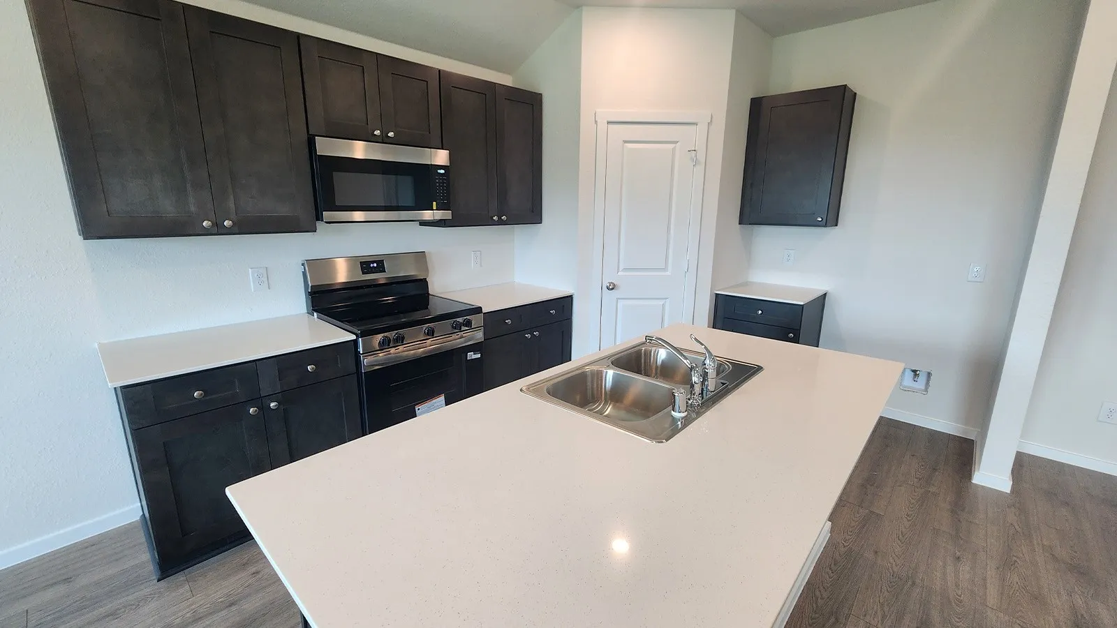 Contemporary kitchen featuring dark wood-finish cabinetry, light countertops, and wood-finish flooring