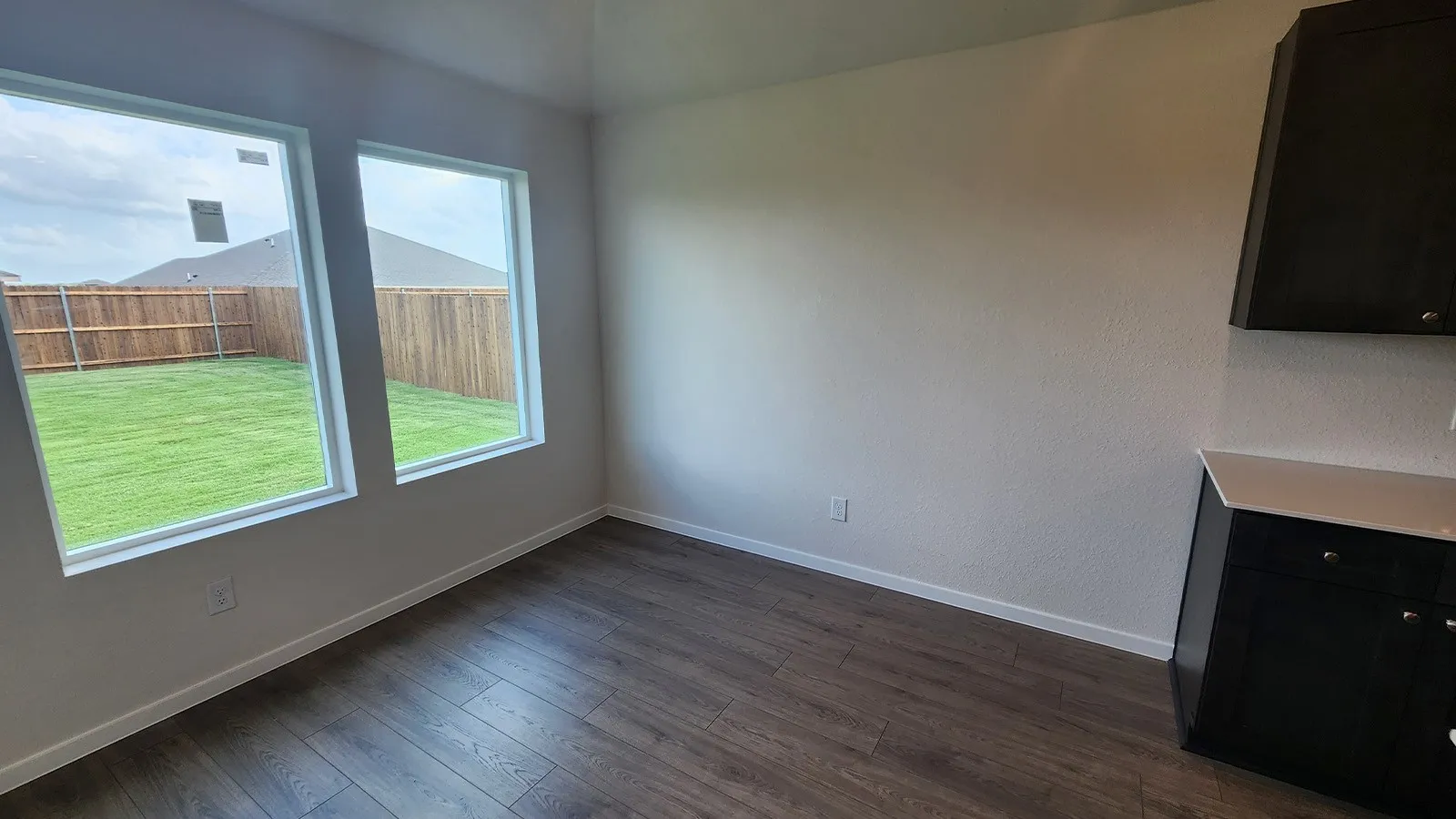 Room featuring wood-finish flooring, two large windows, white baseboards, and a neutral wall color