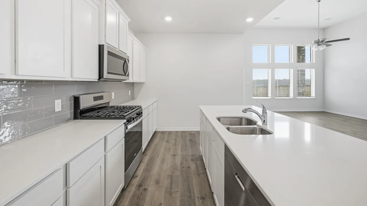 Modern kitchen featuring white cabinetry, light-toned countertops, a stainless steel gas range, and a gray subway tile backsplash