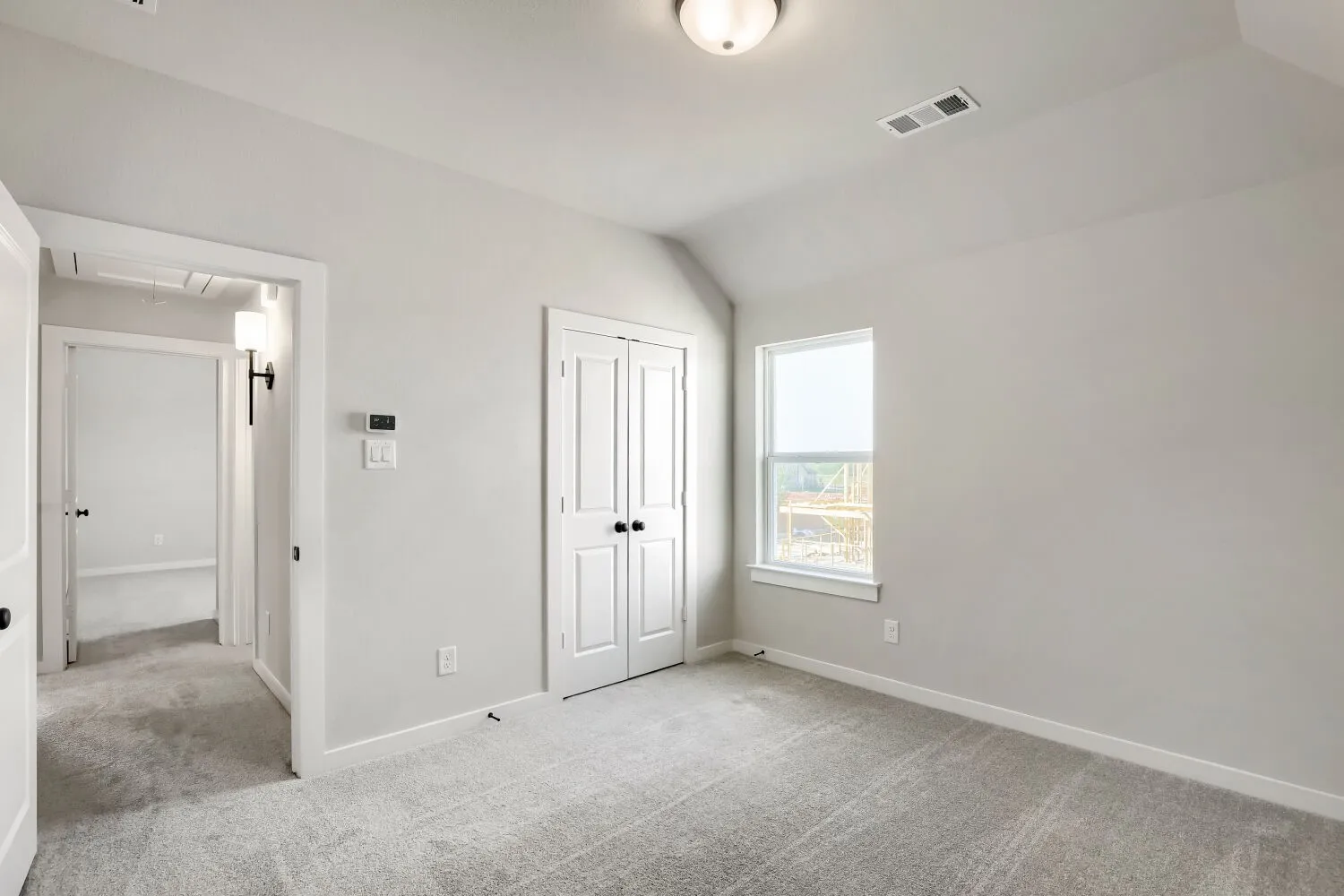 Carpeted room with vaulted ceiling, a single window, and double-door closet