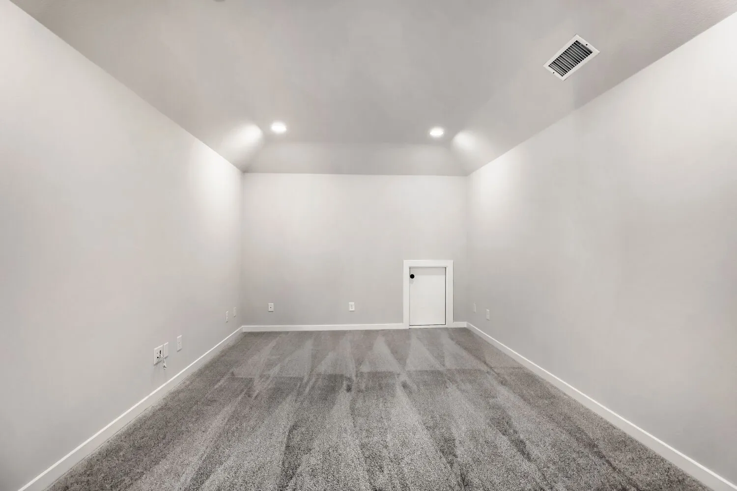 Vaulted ceiling with recessed lighting, gray carpeting, neutral wall color, and a white access door