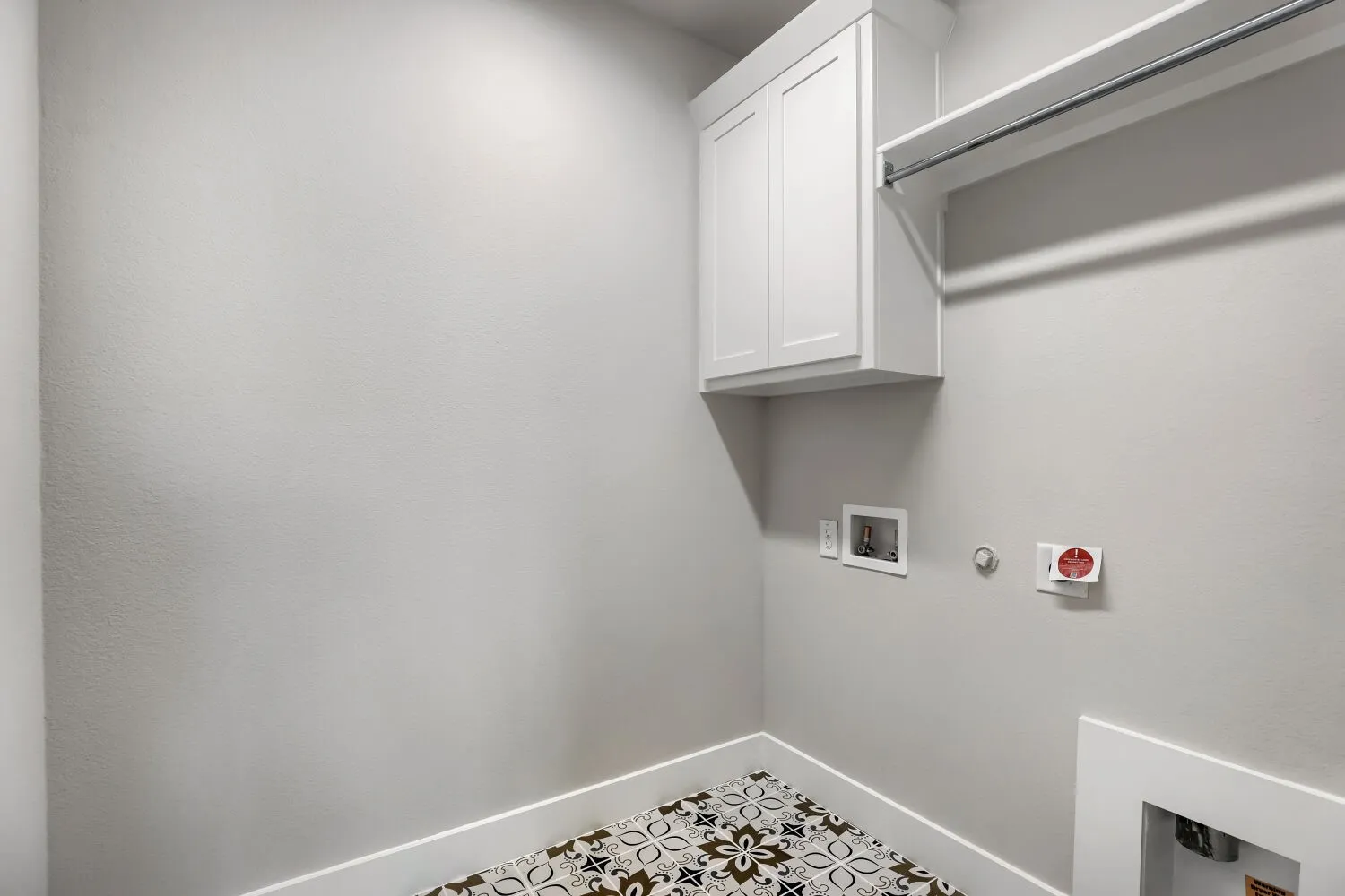 Dedicated laundry room featuring white cabinetry, stainless steel rod, digital temperature controls, and textured tile flooring for durability and easy maintenance