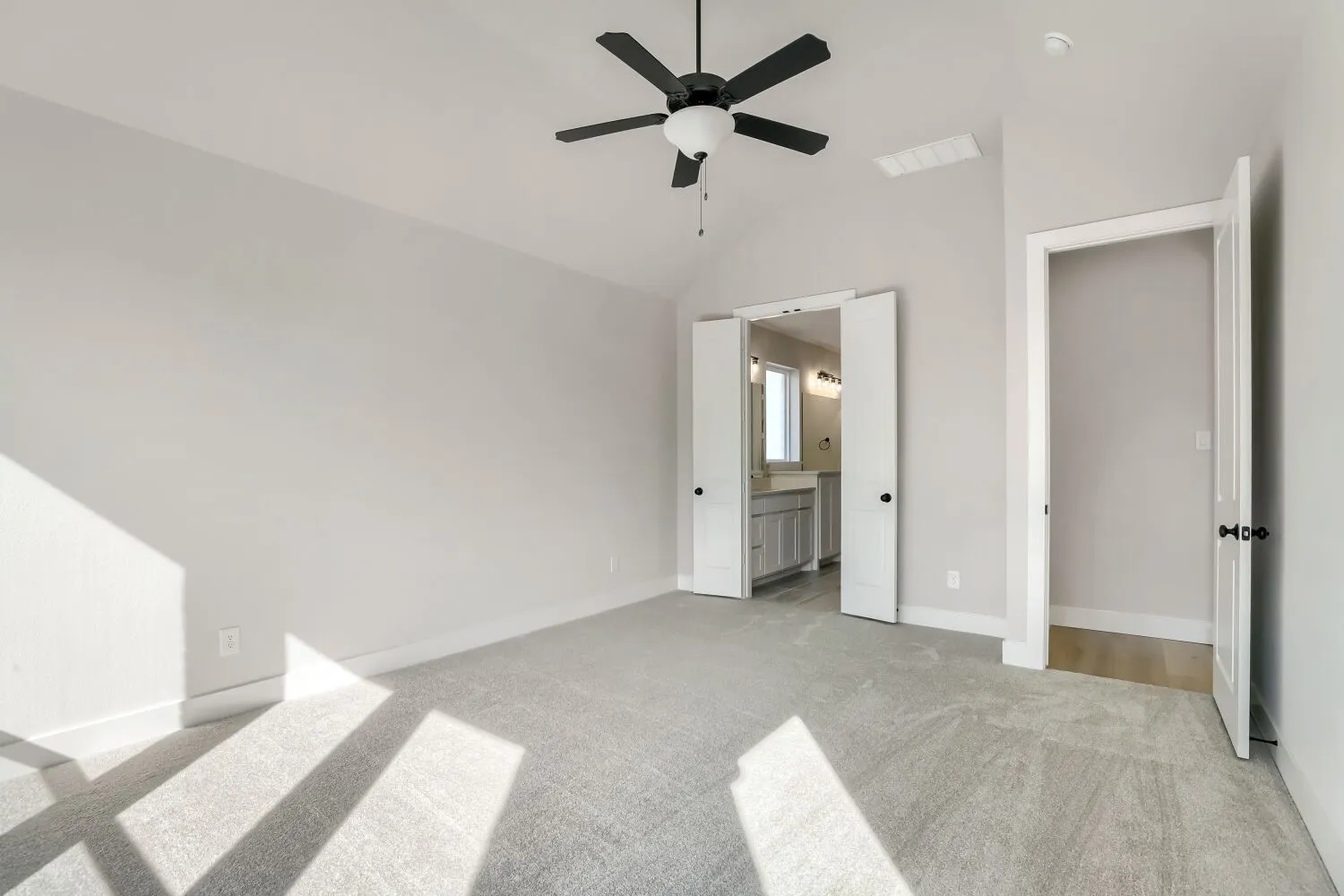 Carpeted room with vaulted ceiling and a ceiling fan