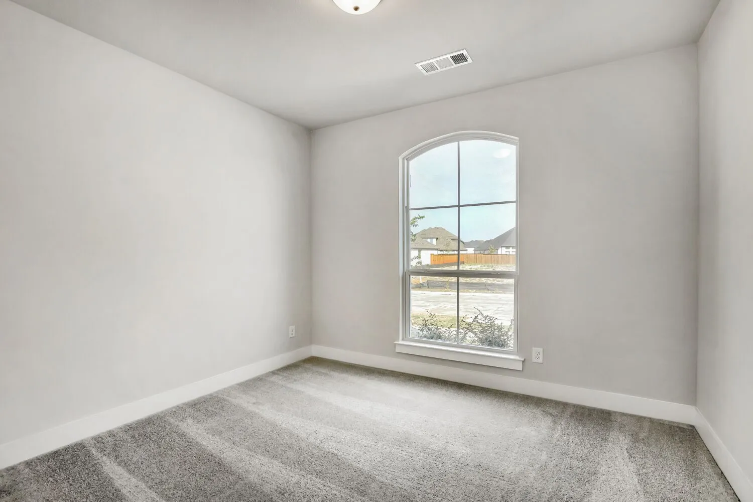 Arched window with gridded panes, light gray wall paint, and gray patterned carpeting