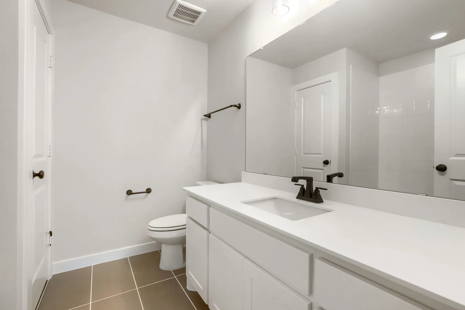 White vanity with an integrated sink, dark bronze-finish faucet, and a large mirror