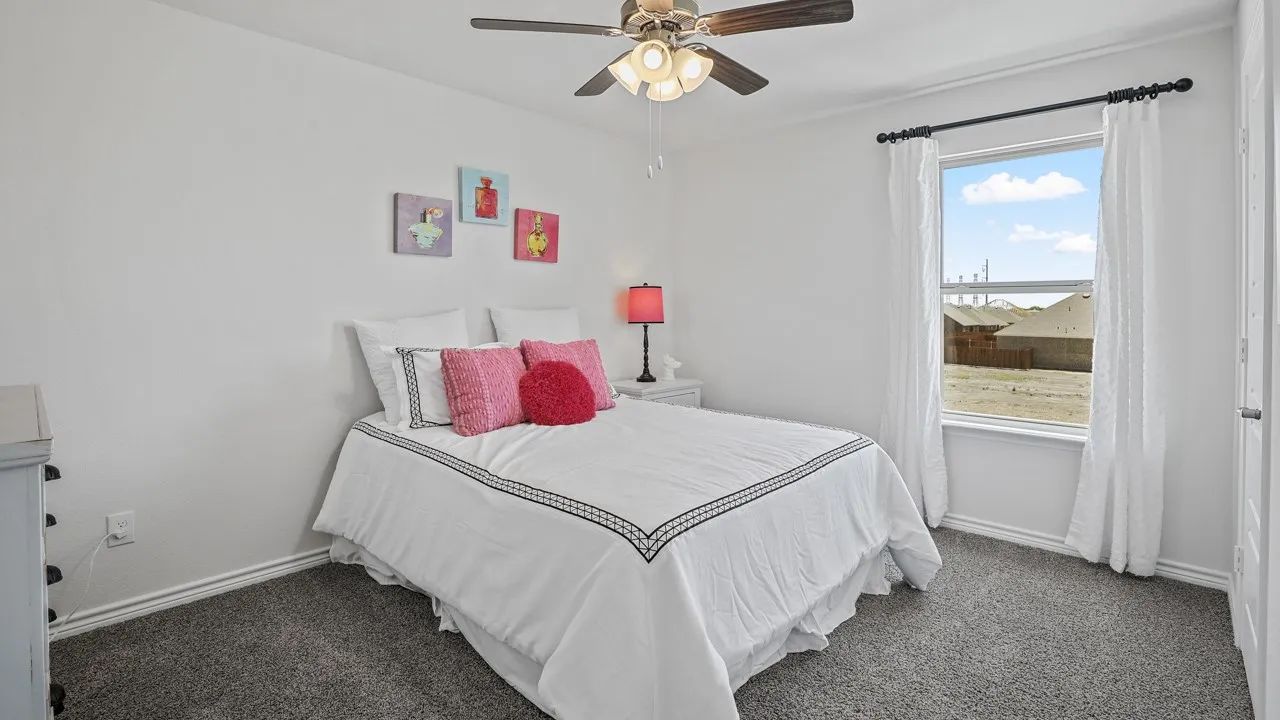 Carpeted room with a ceiling fan, white walls, and a window with white drapes