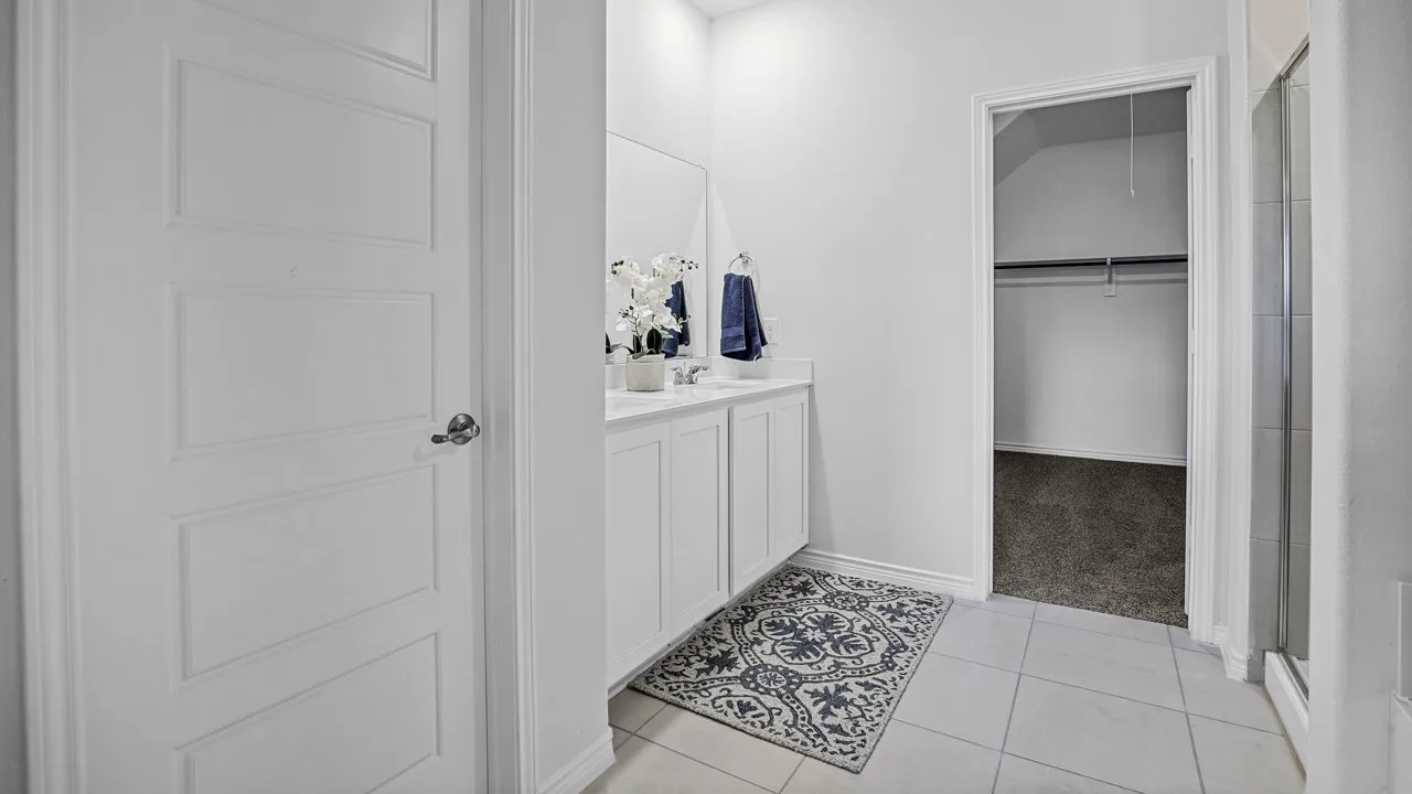 Bathroom vanity featuring dual sinks, white cabinetry, and a light-colored countertop