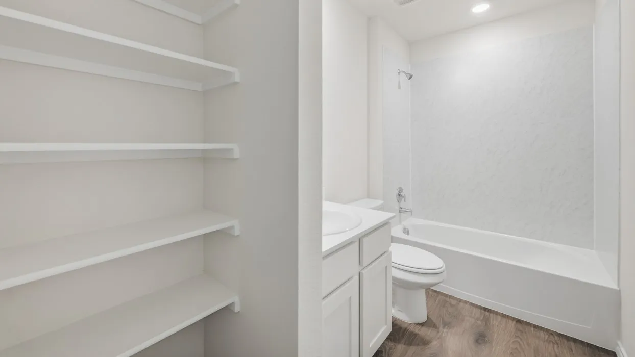 Full bathroom featuring a white tub-shower combination with a textured surround, a vanity with an integrated sink, and wood-finish​​‌​​​​‌​​‌‌​‌‌​​​‌‌​‌​‌​‌​​​‌​​ flooring