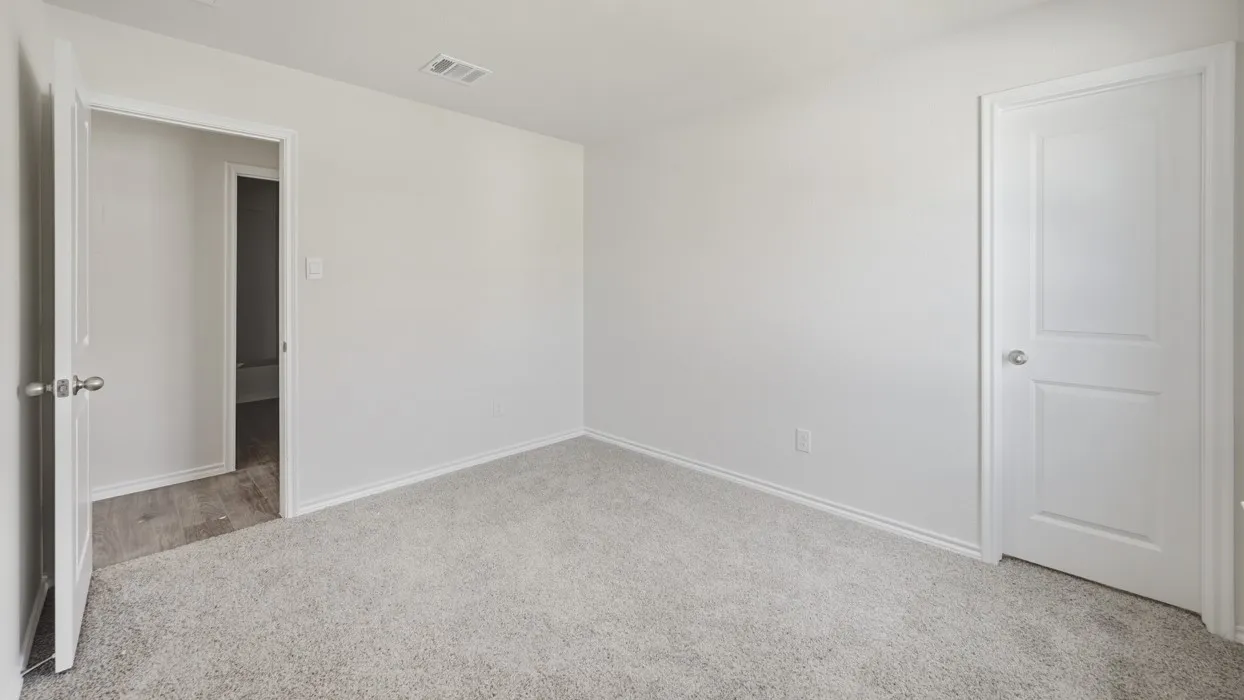 Neutral-toned interior room featuring light gray carpeting and white trim