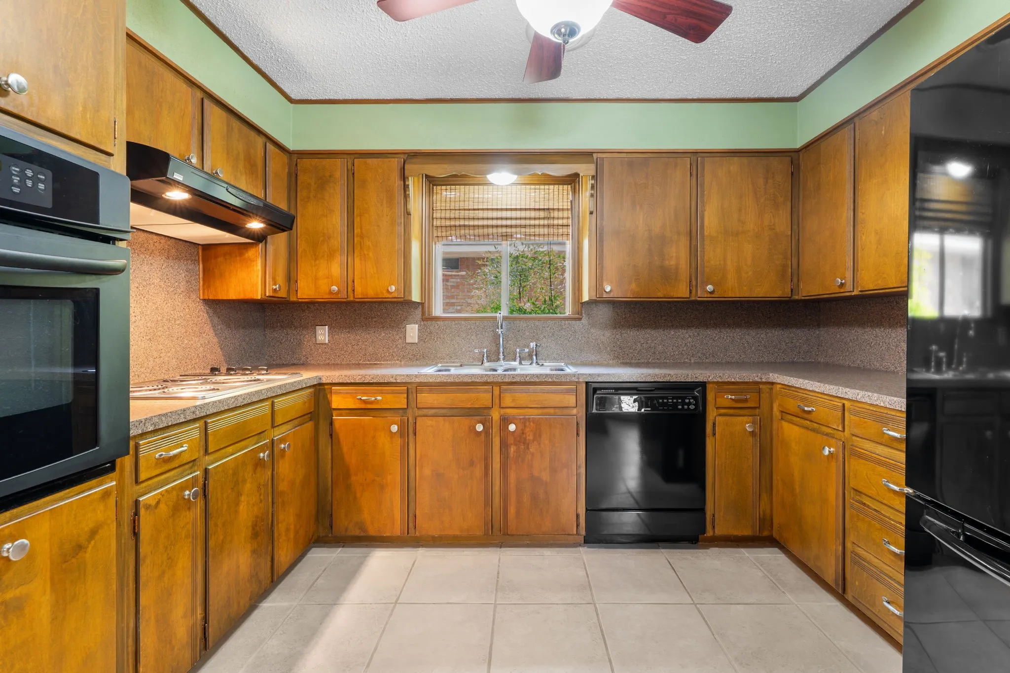 Kitchen featuring wood cabinetry, integrated wall oven, built-in cooktop, and a double basin sink