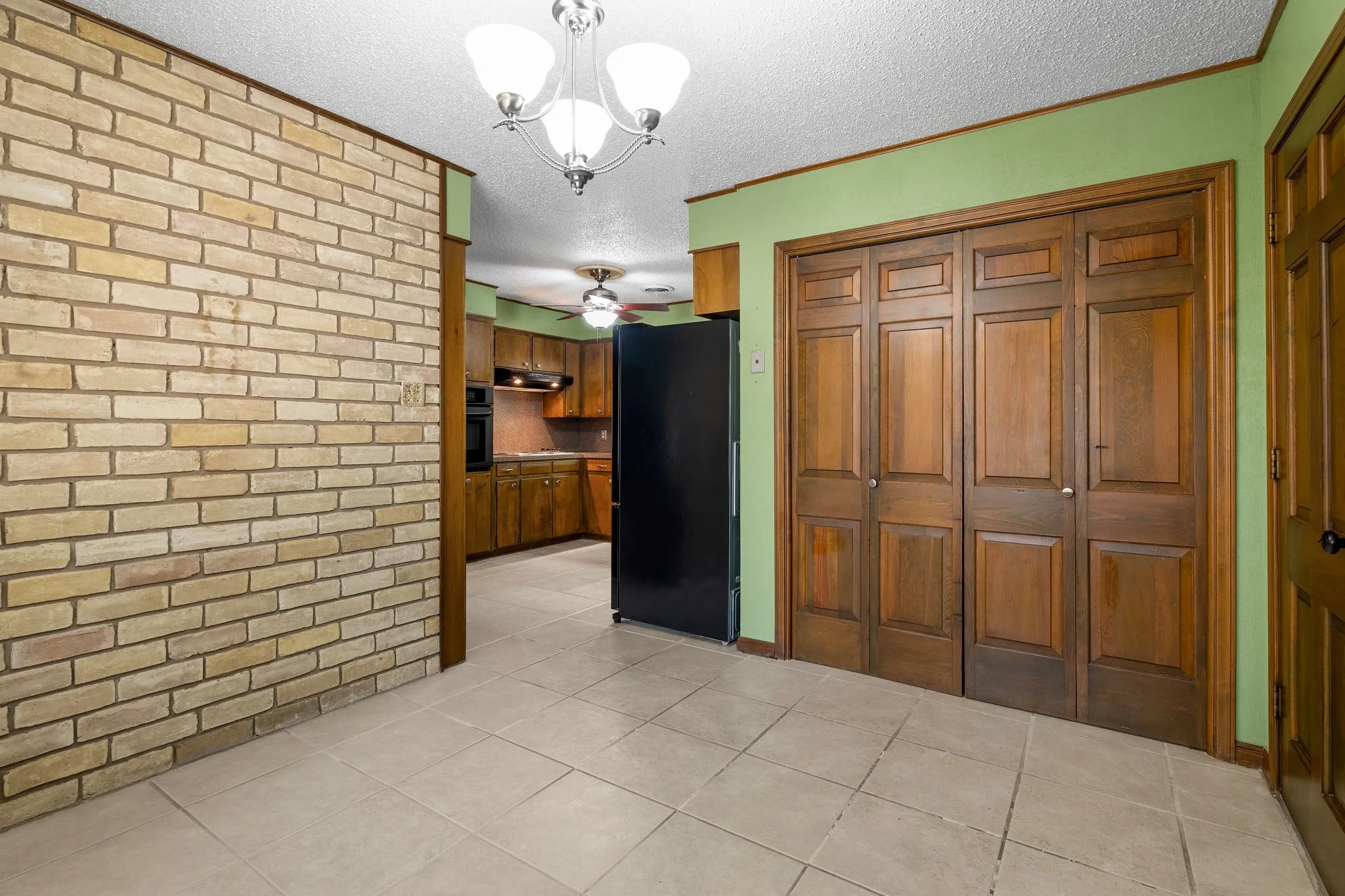 Interior space featuring a blonde brick accent wall and light-toned tile flooring