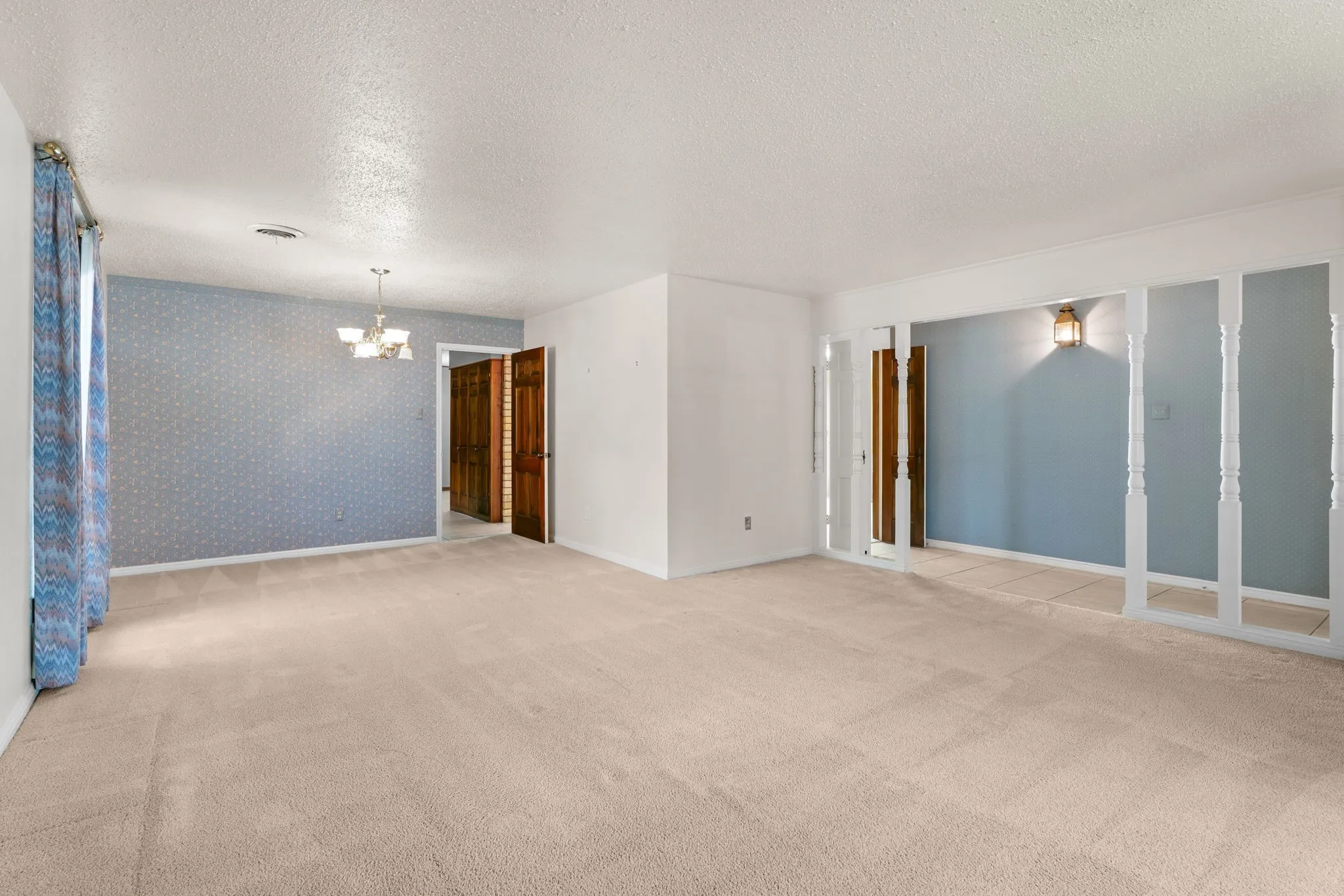 Expansive living area featuring neutral carpeting and textured white ceilings