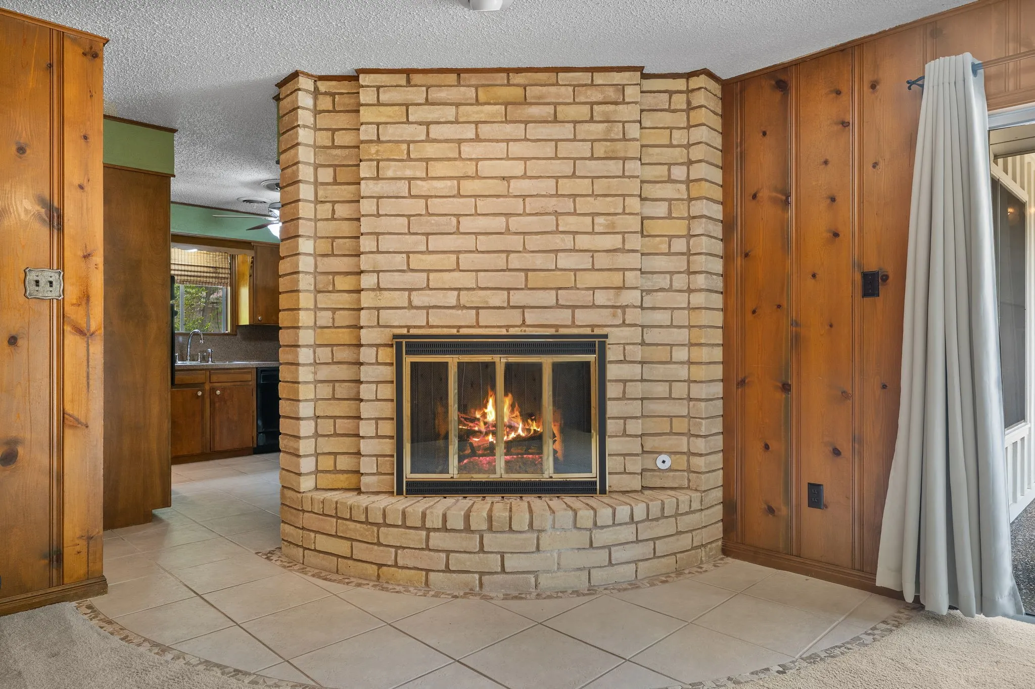 Freestanding brick fireplace with a glass-front firebox, set on a tiled hearth