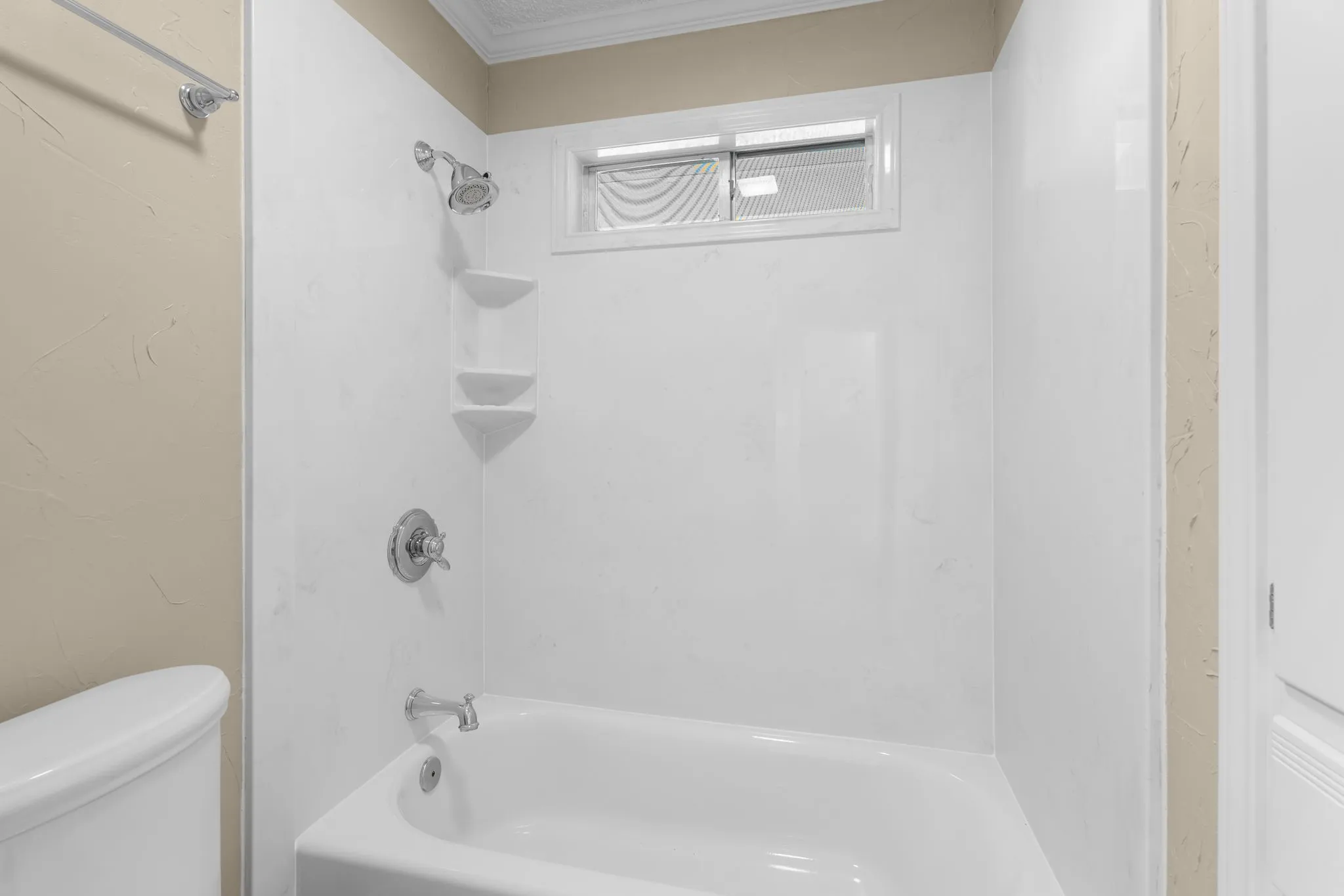 Bathtub with integrated shower, white surround, and chrome fixtures