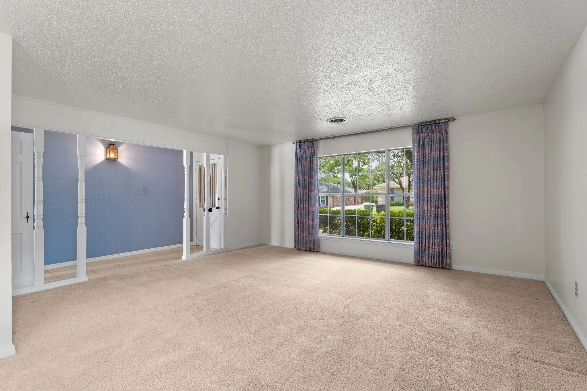 Spacious room featuring neutral carpeting, white walls, and a large front-facing window