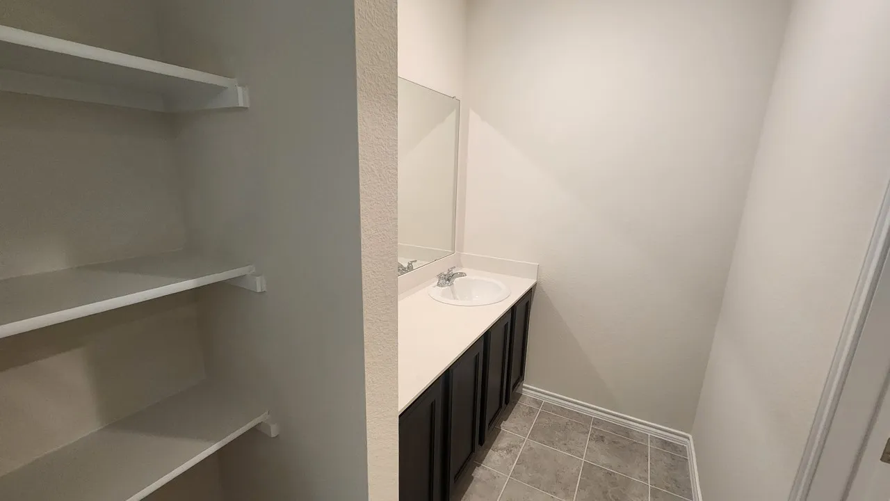 Vanity with a white countertop and integrated sink, dark wood-finish cabinetry, and a framed mirror