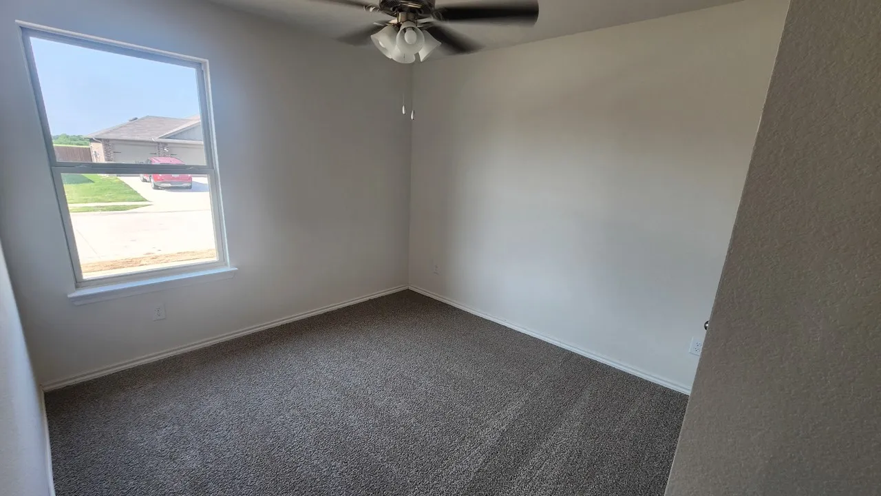 Room featuring neutral-toned walls, gray carpet flooring, and a white-trimmed window