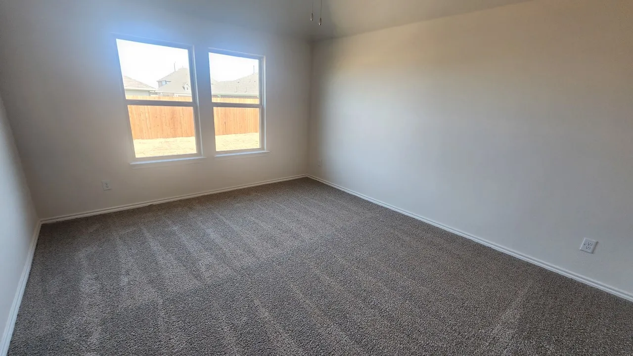 Neutral color palette with textured carpeting, white walls, dual windows, and ceiling fan