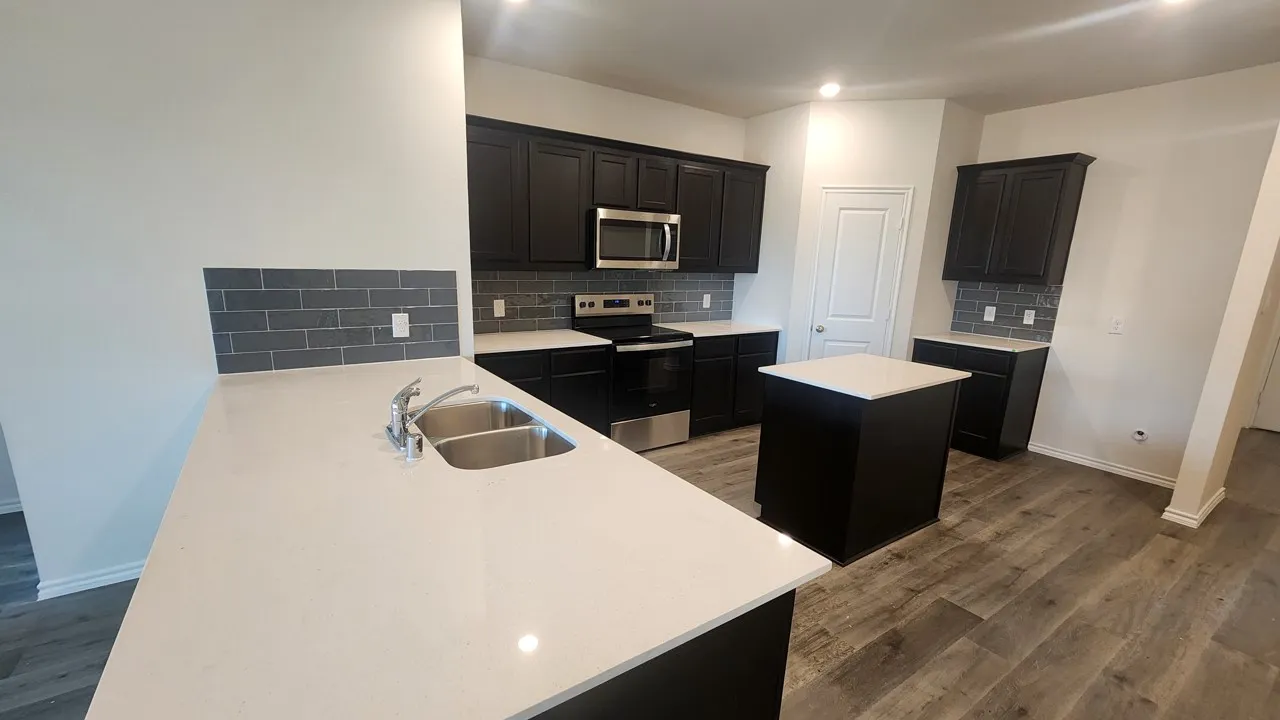 Kitchen featuring dark cabinetry, light countertops, subway tile backsplash, stainless steel appliances, and wood-finish flooring