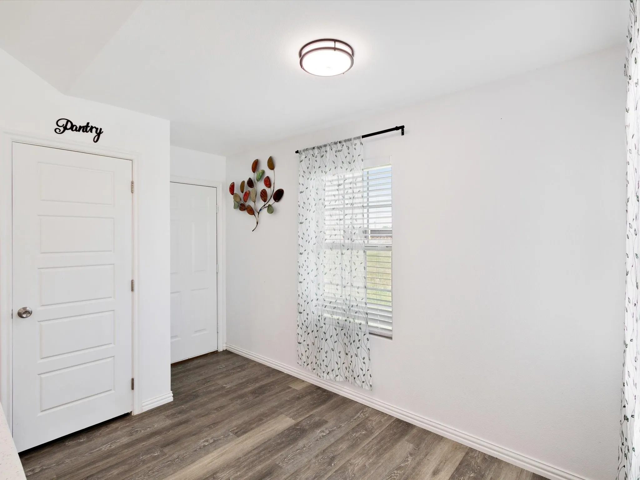 Interior space featuring wood-finish flooring, white baseboards, and a window with horizontal blinds
